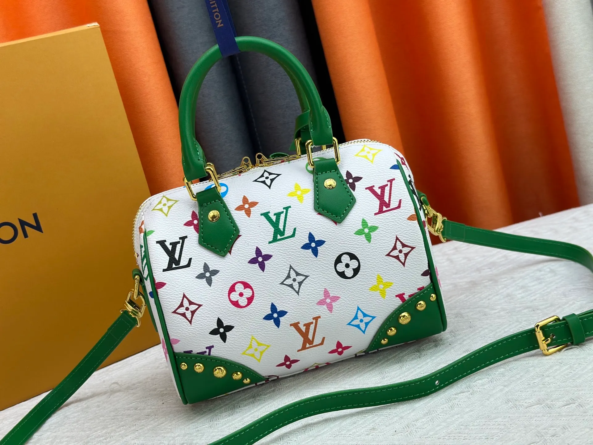 P260 upgraded original M58953 M46234 M46222 Speedy Bandoulière 20 handbag is made of soft coated canvas, and the full-length Monogram pattern is traced in colorful rainbow tones, highlighting the smart style of the Louis Vuitton x Murakami reissue series. The Toron handle and detachable shoulder strap are constructed of cow leather, the metal corners recall classic luggage elements, and the bow-shaped key bag and padlock add brand touches. Dimensions: 20.5 x 13.5 x 12.0 cm (length x height x width)