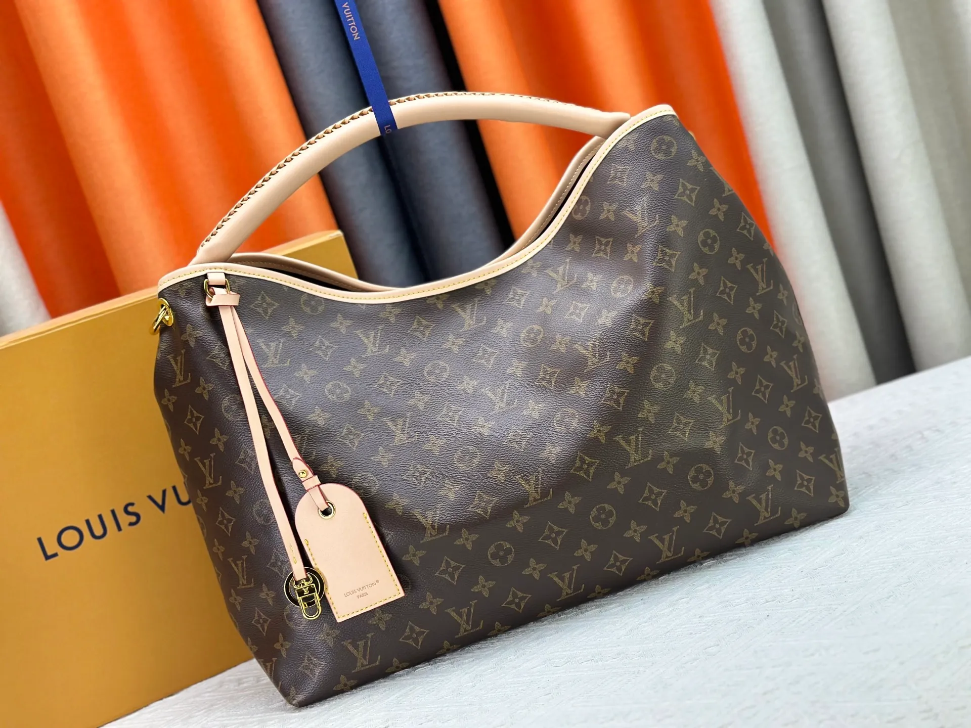 P300 upgrades the original M25877 Again bag, a new interpretation of the iconic Artsy design first launched in 2010, now more flexible, more iconic and more refined. Rooted in LV’s DNA, this bag pays homage to Louis Vuitton’s craftsmanship with its classic Monogram canvas base, hand-woven handles and customizable name tag. It's spacious enough to hold a laptop and opens to reveal multiple pockets. Gold hooks can be used to hang playful accessories! ! Size:50x30x15.5CM