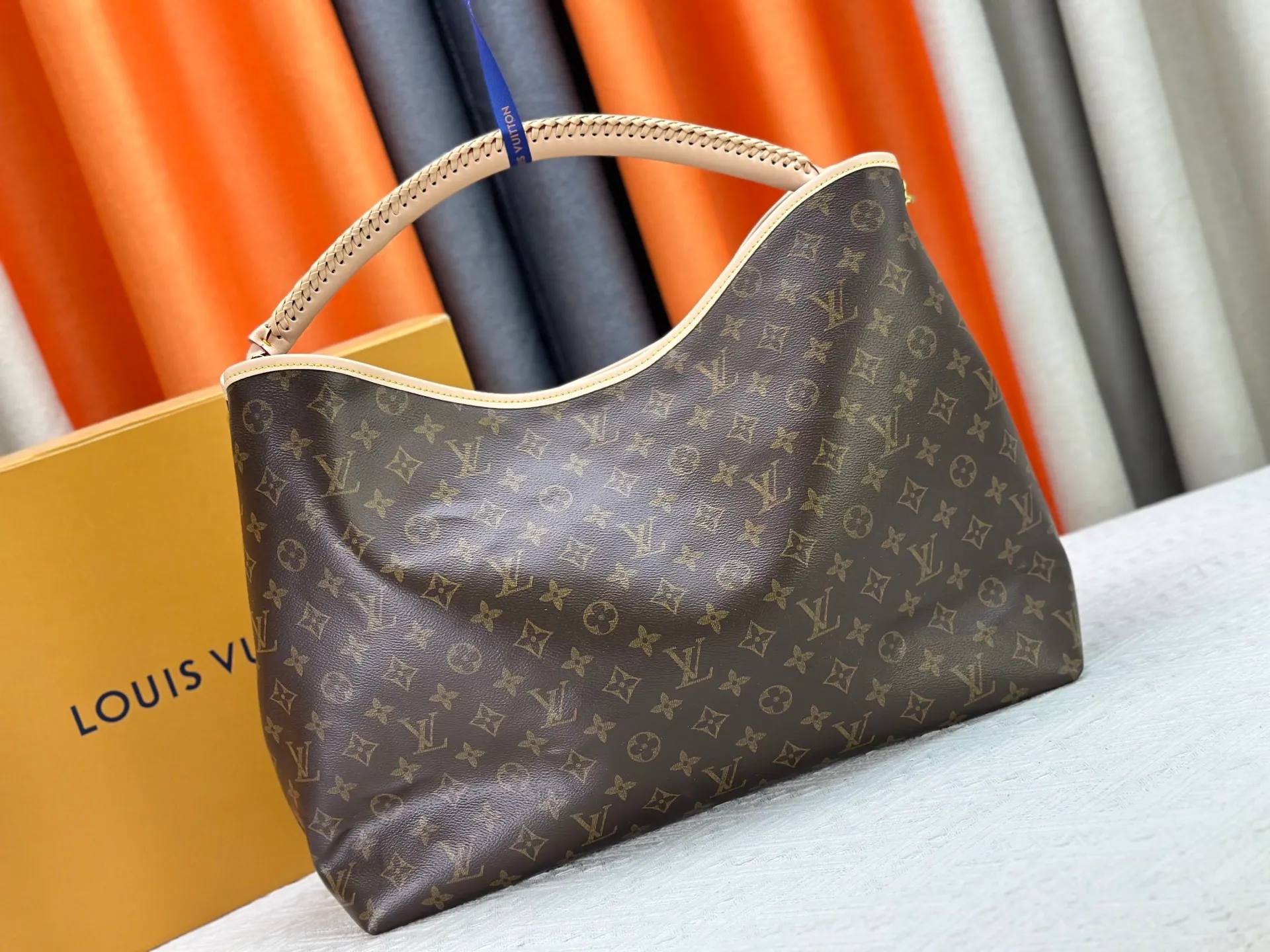 P300 upgrades the original M25877 Again bag, a new interpretation of the iconic Artsy design first launched in 2010, now more flexible, more iconic and more refined. Rooted in LV’s DNA, this bag pays homage to Louis Vuitton’s craftsmanship with its classic Monogram canvas base, hand-woven handles and customizable name tag. It's spacious enough to hold a laptop and opens to reveal multiple pockets. Gold hooks can be used to hang playful accessories! ! Size:50x30x15.5CM