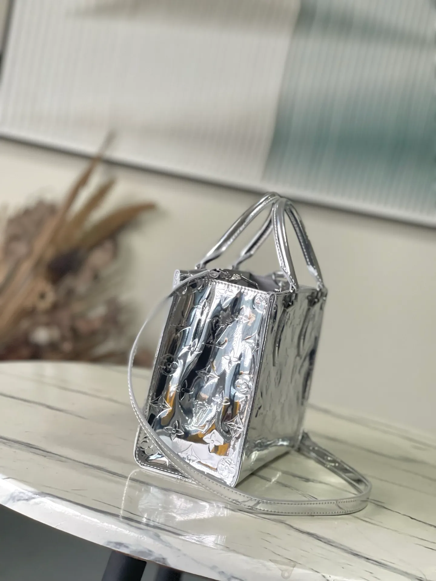 💰1120 Top Original M26373 Silver This OnTheGo small handbag joins the Ski series in the Monogram Miroir version. Laminated canvas ensures durability. Silver hues and tonal hardware create a gleaming look. Built-in pockets can store daily necessities such as small books. Size: 25*11.5*19cm.