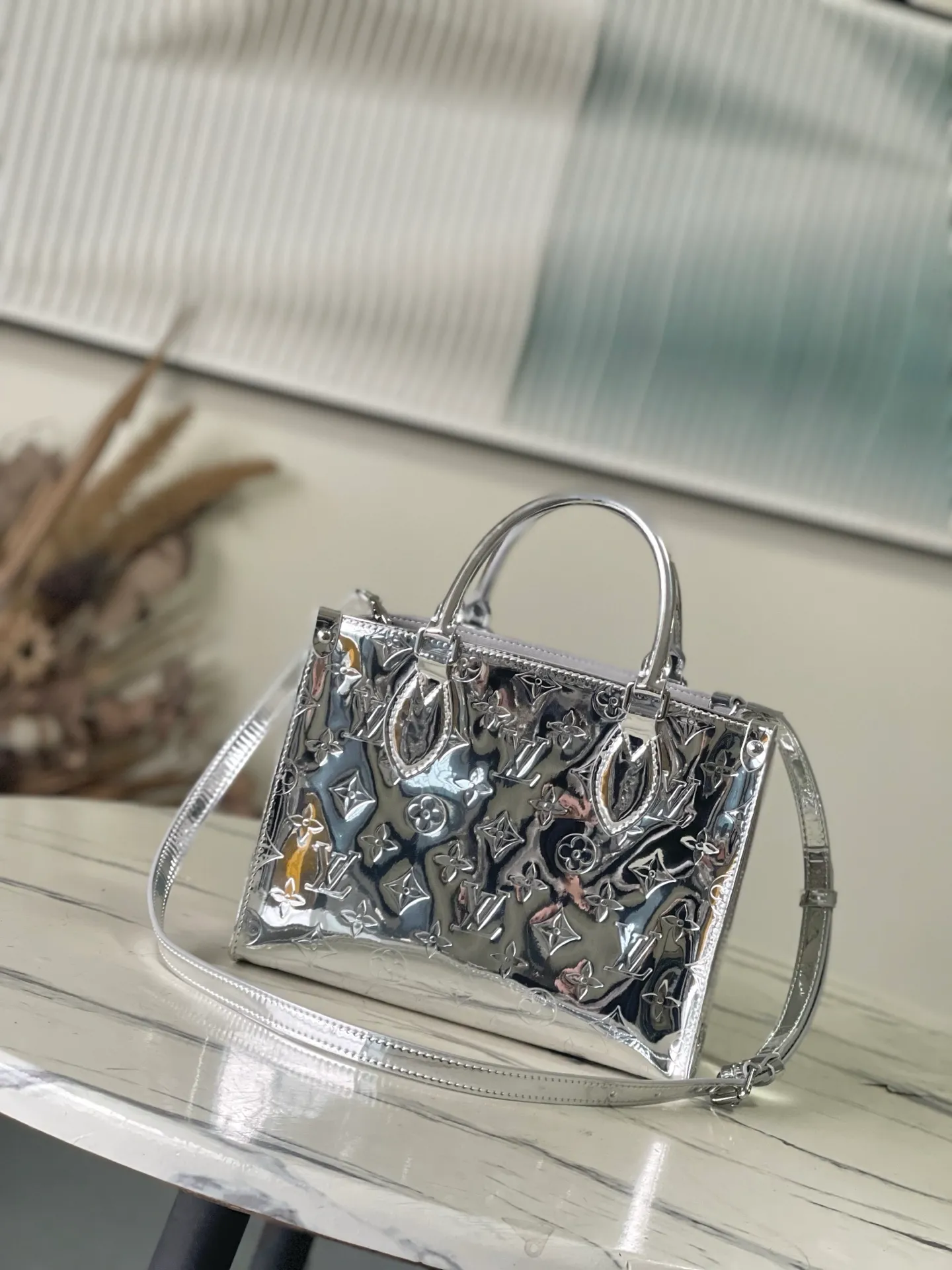 💰1120 Top Original M26373 Silver This OnTheGo small handbag joins the Ski series in the Monogram Miroir version. Laminated canvas ensures durability. Silver hues and tonal hardware create a gleaming look. Built-in pockets can store daily necessities such as small books. Size: 25*11.5*19cm.
