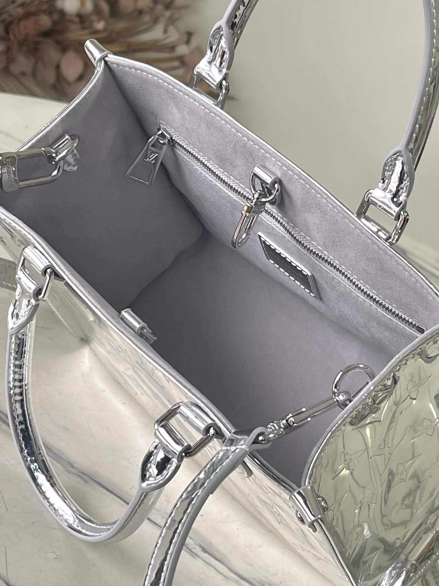 💰1120 Top Original M26373 Silver This OnTheGo small handbag joins the Ski series in the Monogram Miroir version. Laminated canvas ensures durability. Silver hues and tonal hardware create a gleaming look. Built-in pockets can store daily necessities such as small books. Size: 25*11.5*19cm.