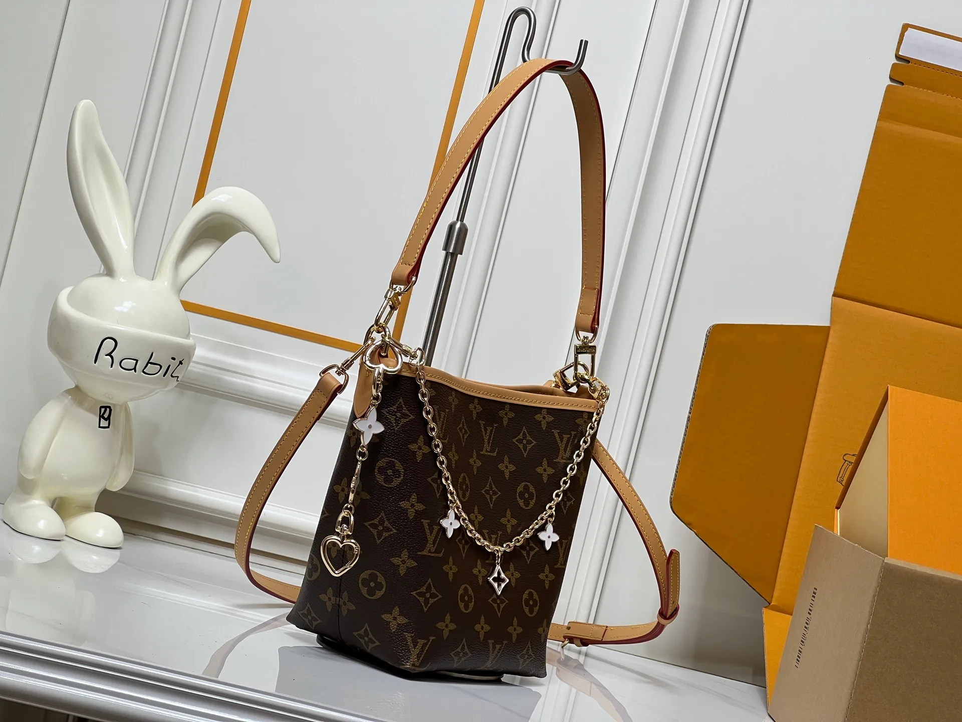 Batch 300💰M25666 All In BB Handbag It is made of the iconic Monogram presbyopic canvas, and the bag shape is simple yet stylish. Paired with a red leather shoulder strap, it can be worn on one shoulder or across the body, and can be carried flexibly. The body of the bag is also decorated with metal chain charms with brand elements and flower shapes, which adds a sense of sophistication and design to the whole. It not only retains the classic charm of LV, but also shows a unique fashion style through detailed design. It is a good choice to enhance the style and texture in daily matching. Size: 17x20x15cm