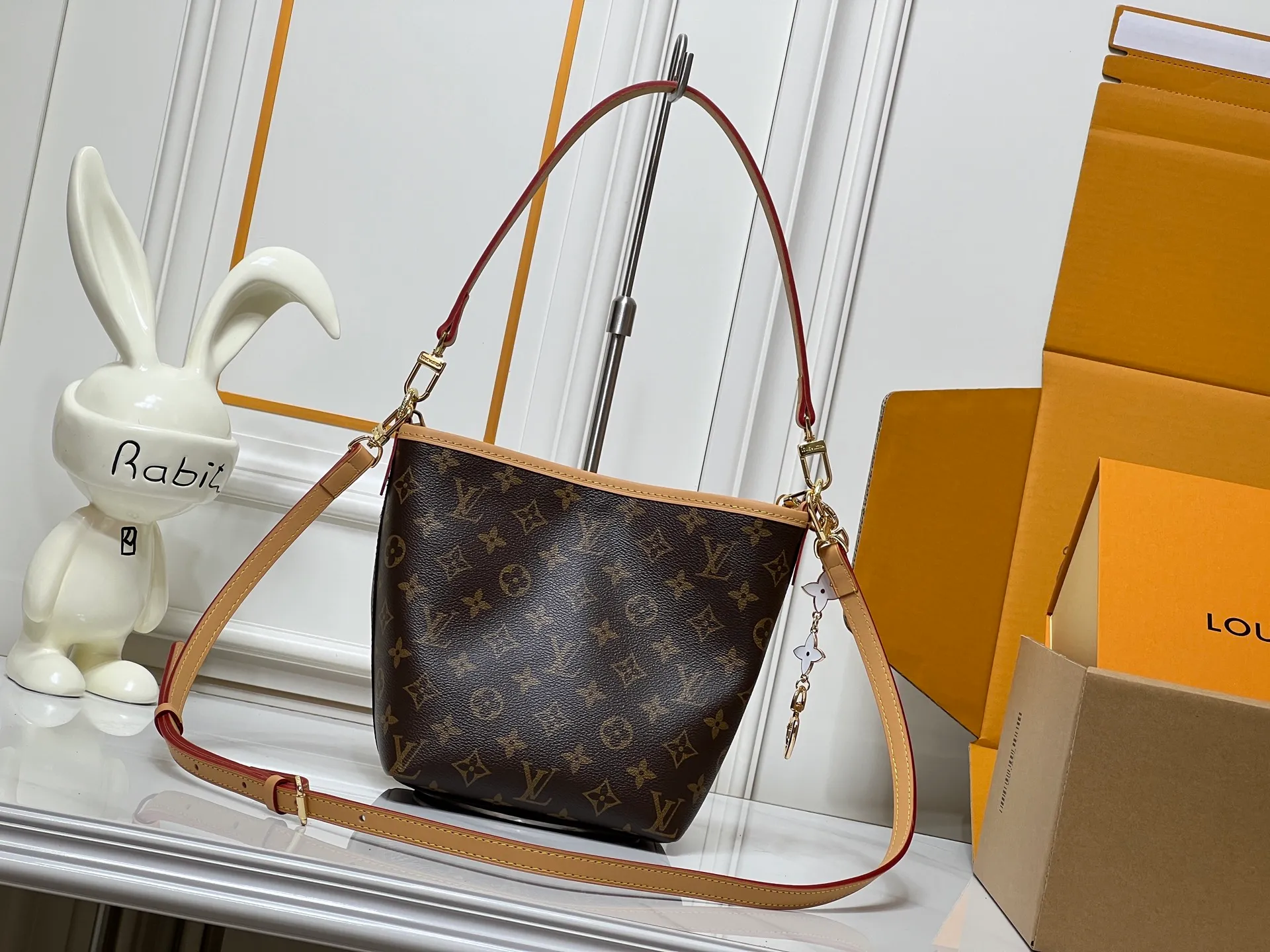 Batch 300💰M25666 All In BB Handbag It is made of the iconic Monogram presbyopic canvas, and the bag shape is simple yet stylish. Paired with a red leather shoulder strap, it can be worn on one shoulder or across the body, and can be carried flexibly. The body of the bag is also decorated with metal chain charms with brand elements and flower shapes, which adds a sense of sophistication and design to the whole. It not only retains the classic charm of LV, but also shows a unique fashion style through detailed design. It is a good choice to enhance the style and texture in daily matching. Size: 17x20x15cm