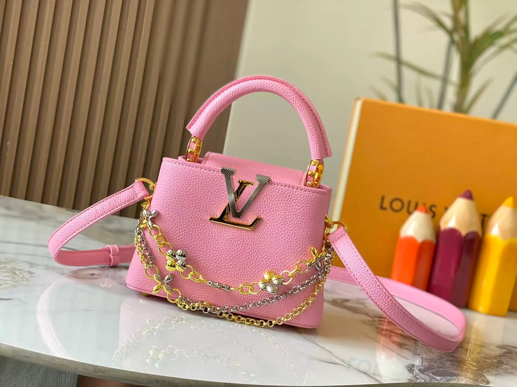 P480 [Guangzhou top quality original version] M26351 Pink This modern version of Capucines mini is made of timeless Taurillon leather and equipped with a jewelry-inspired Infinity chain. The bag is decorated with double galvanized metal parts, including the iconic Monogram floral pattern, and the LV Initials logo created with sunburst technology, creating a sundial-like light and shadow effect. The bag has multiple pockets and a detachable shoulder strap, allowing it to be carried on one shoulder or across the body. 14 x 8 x 21 cm (height x width x length)