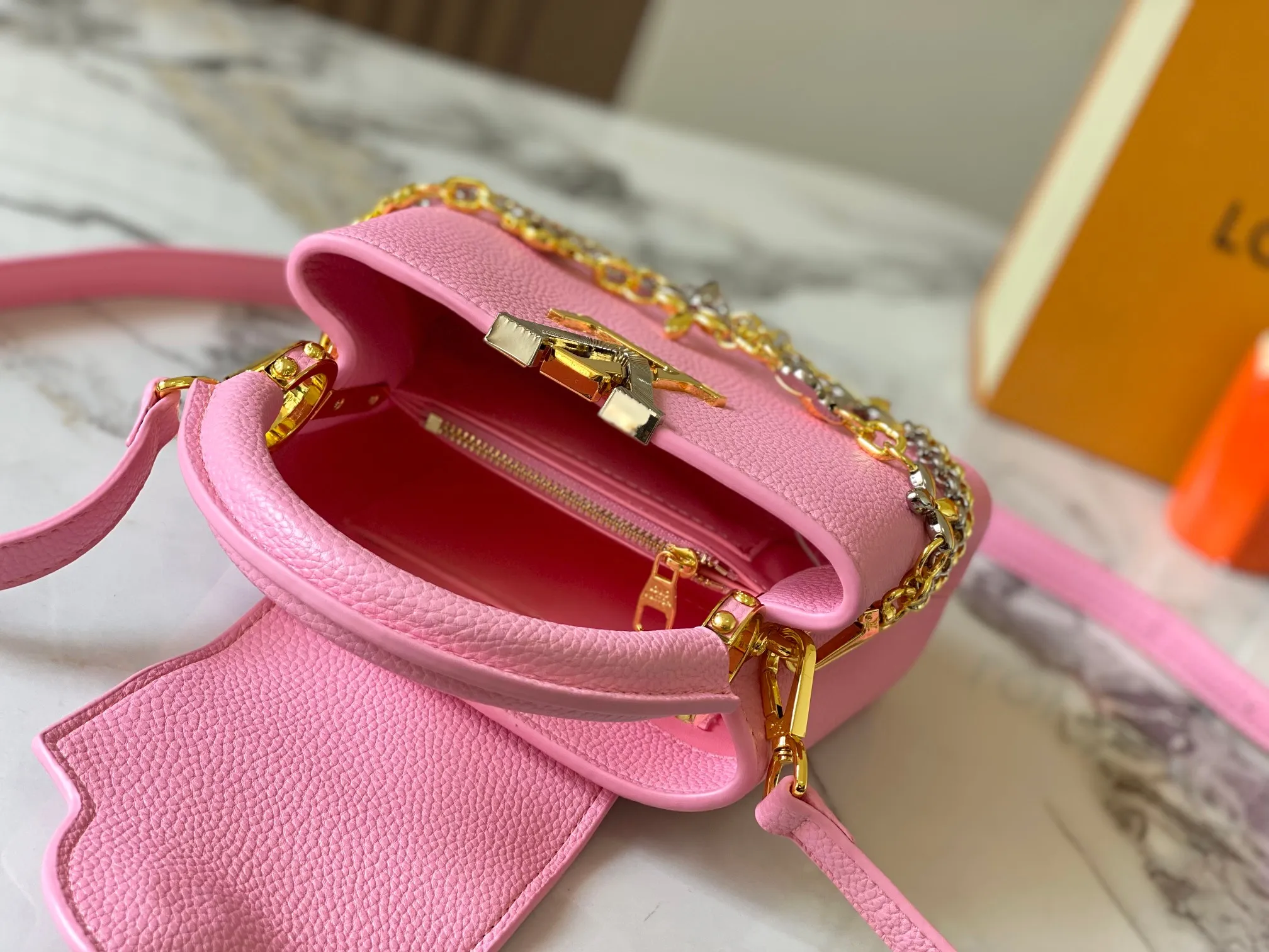 P480 [Guangzhou top quality original version] M26351 Pink This modern version of Capucines mini is made of timeless Taurillon leather and equipped with a jewelry-inspired Infinity chain. The bag is decorated with double galvanized metal parts, including the iconic Monogram floral pattern, and the LV Initials logo created with sunburst technology, creating a sundial-like light and shadow effect. The bag has multiple pockets and a detachable shoulder strap, allowing it to be carried on one shoulder or across the body. 14 x 8 x 21 cm (height x width x length)