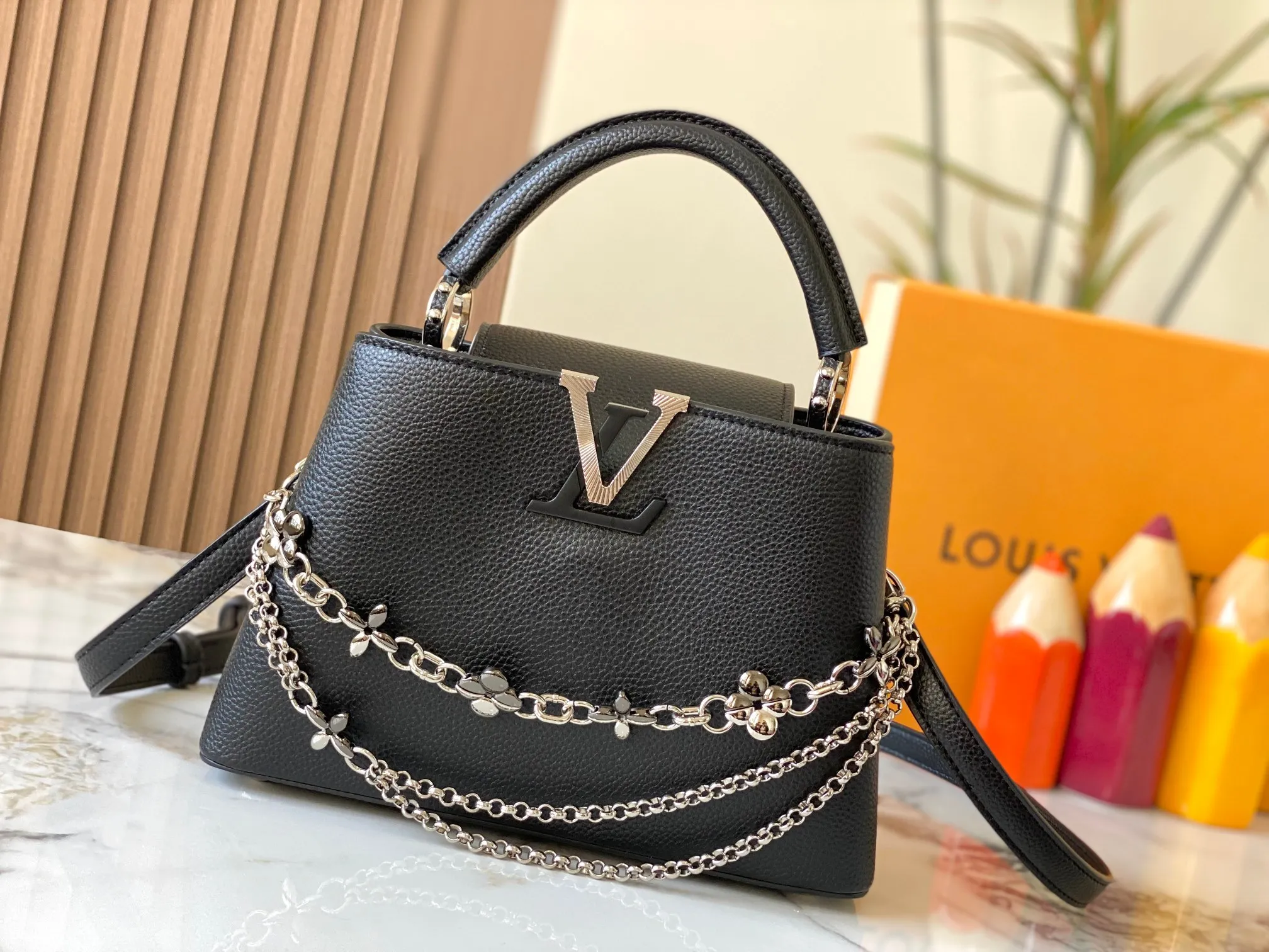 P500 [Guangzhou top quality original version] M26532 black silver This modern version of Capucines BB is made of timeless Taurillon leather and equipped with a jewelry-inspired Infinity chain. The bag is decorated with double galvanized metal parts, including the iconic Monogram floral pattern, and the LV Initials logo created with sunburst technology, creating a sundial-like light and shadow effect. The bag has multiple pockets and a detachable shoulder strap, allowing it to be carried on one shoulder or across the body. 27 x 17.3 x 9 (cm) (length x height x width)