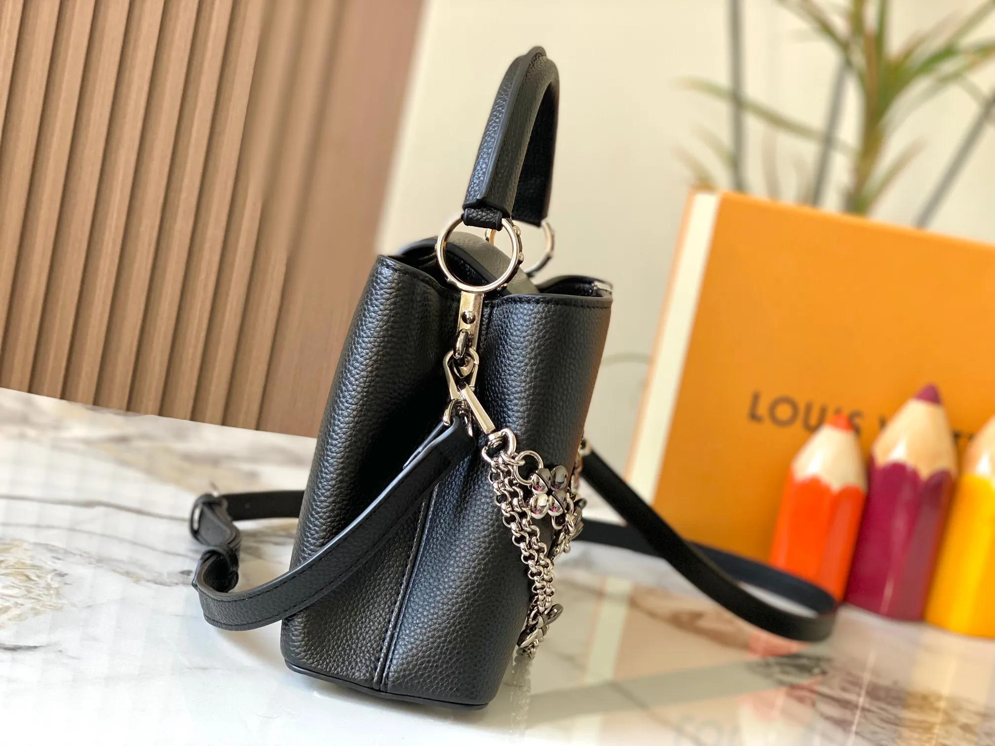 P500 [Guangzhou top quality original version] M26532 black silver This modern version of Capucines BB is made of timeless Taurillon leather and equipped with a jewelry-inspired Infinity chain. The bag is decorated with double galvanized metal parts, including the iconic Monogram floral pattern, and the LV Initials logo created with sunburst technology, creating a sundial-like light and shadow effect. The bag has multiple pockets and a detachable shoulder strap, allowing it to be carried on one shoulder or across the body. 27 x 17.3 x 9 (cm) (length x height x width)