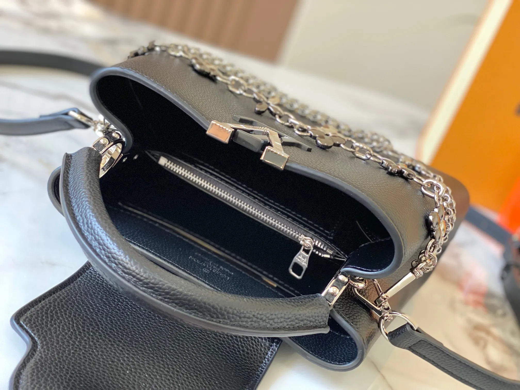 P500 [Guangzhou top quality original version] M26532 black silver This modern version of Capucines BB is made of timeless Taurillon leather and equipped with a jewelry-inspired Infinity chain. The bag is decorated with double galvanized metal parts, including the iconic Monogram floral pattern, and the LV Initials logo created with sunburst technology, creating a sundial-like light and shadow effect. The bag has multiple pockets and a detachable shoulder strap, allowing it to be carried on one shoulder or across the body. 27 x 17.3 x 9 (cm) (length x height x width)