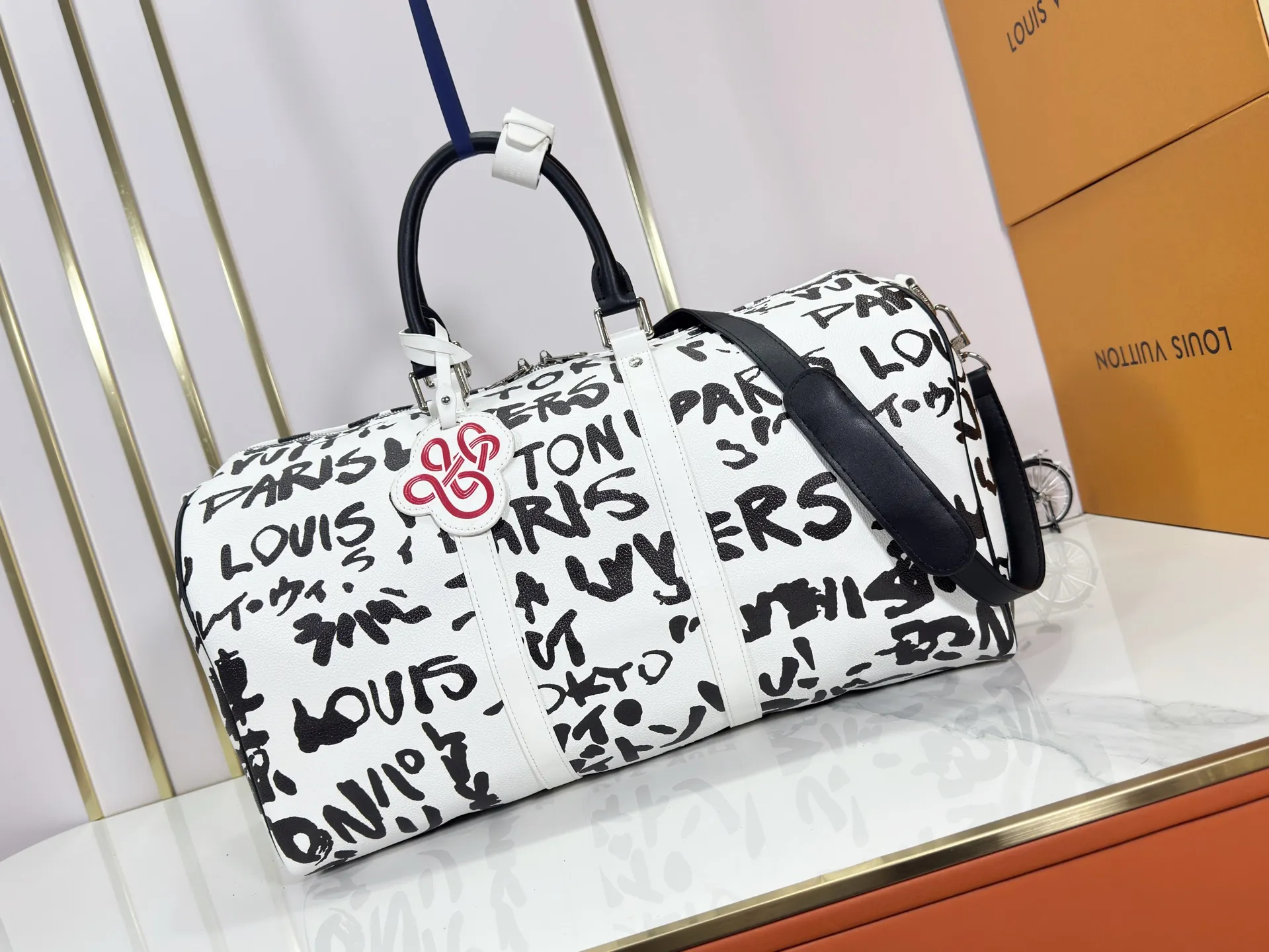 P340 M40805 M40804 M41416 The upgraded original Keepall Bandoulière 50 travel bag was jointly created by Japanese designers Nigo and Pharrell Williams. It is laid out with elegant plaid on the cow leather, and then has eye-catching words written in French and Japanese. A cotton lining pattern bears witness to Nigo's artistic vision, and a removable LV Dynasty nameplate highlights the brand's identity.  29 cm