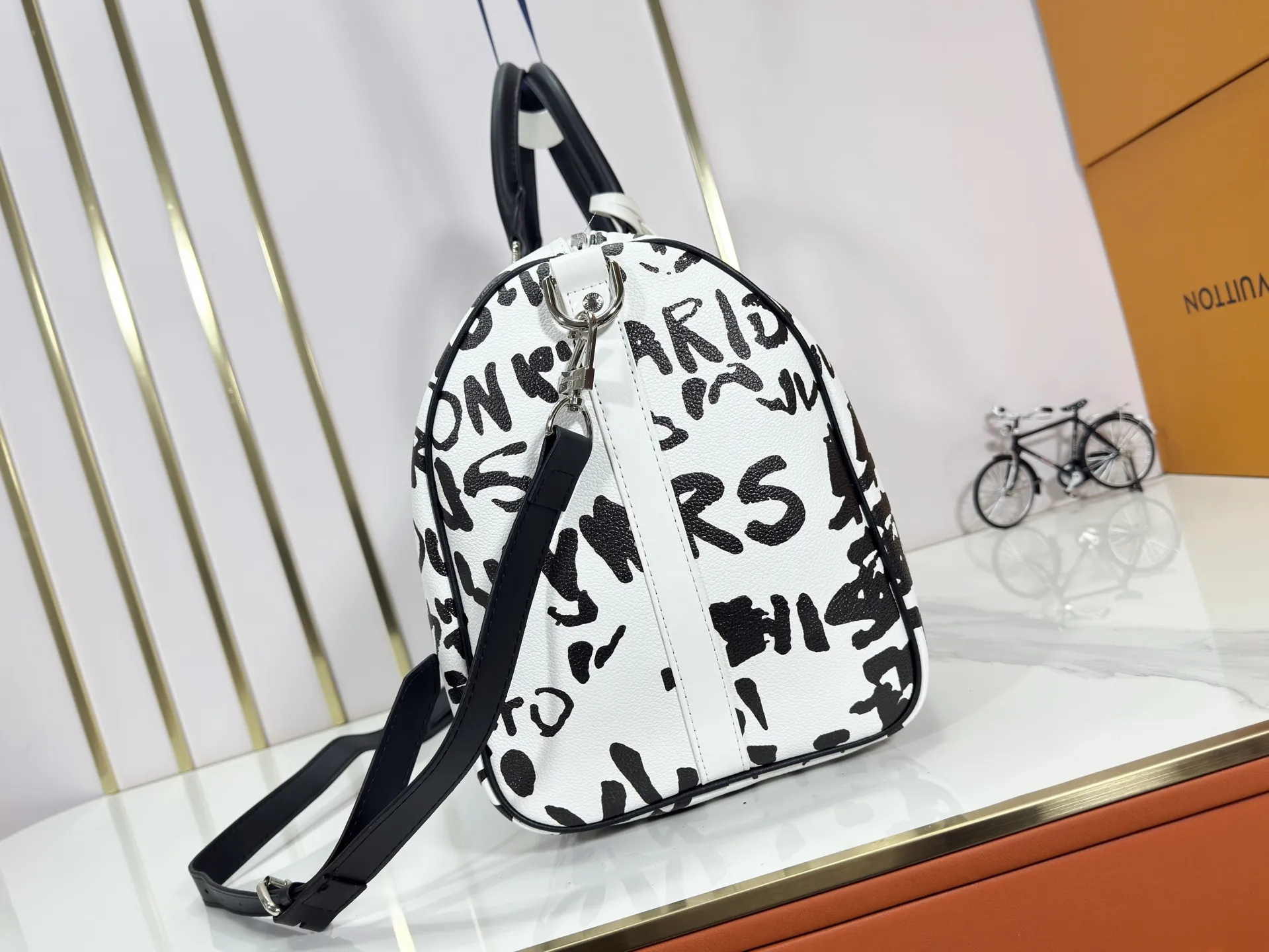 P340 M40805 M40804 M41416 The upgraded original Keepall Bandoulière 50 travel bag was jointly created by Japanese designers Nigo and Pharrell Williams. It is laid out with elegant plaid on the cow leather, and then has eye-catching words written in French and Japanese. A cotton lining pattern bears witness to Nigo's artistic vision, and a removable LV Dynasty nameplate highlights the brand's identity.  29 cm