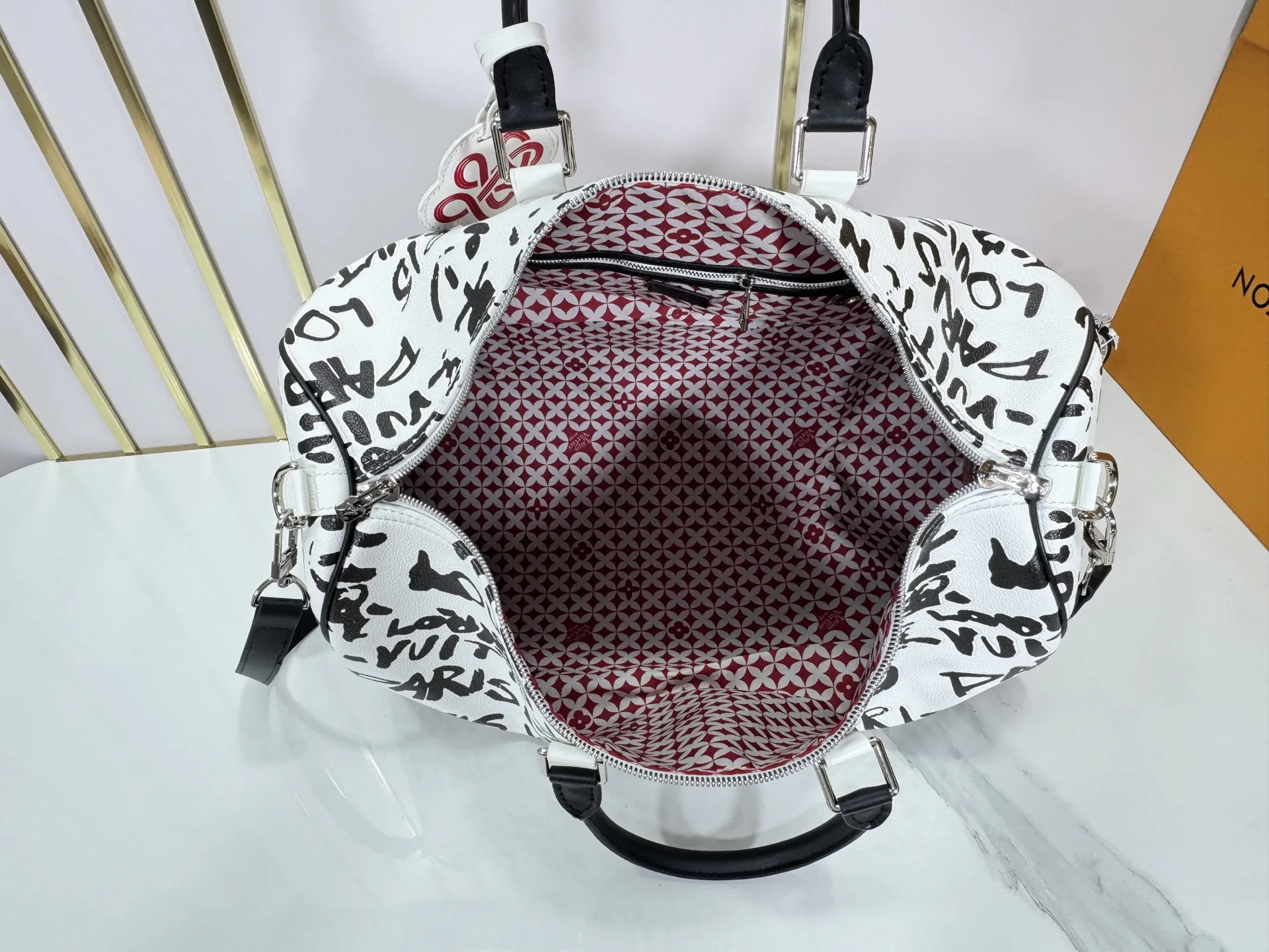P340 M40805 M40804 M41416 The upgraded original Keepall Bandoulière 50 travel bag was jointly created by Japanese designers Nigo and Pharrell Williams. It is laid out with elegant plaid on the cow leather, and then has eye-catching words written in French and Japanese. A cotton lining pattern bears witness to Nigo's artistic vision, and a removable LV Dynasty nameplate highlights the brand's identity.  29 cm