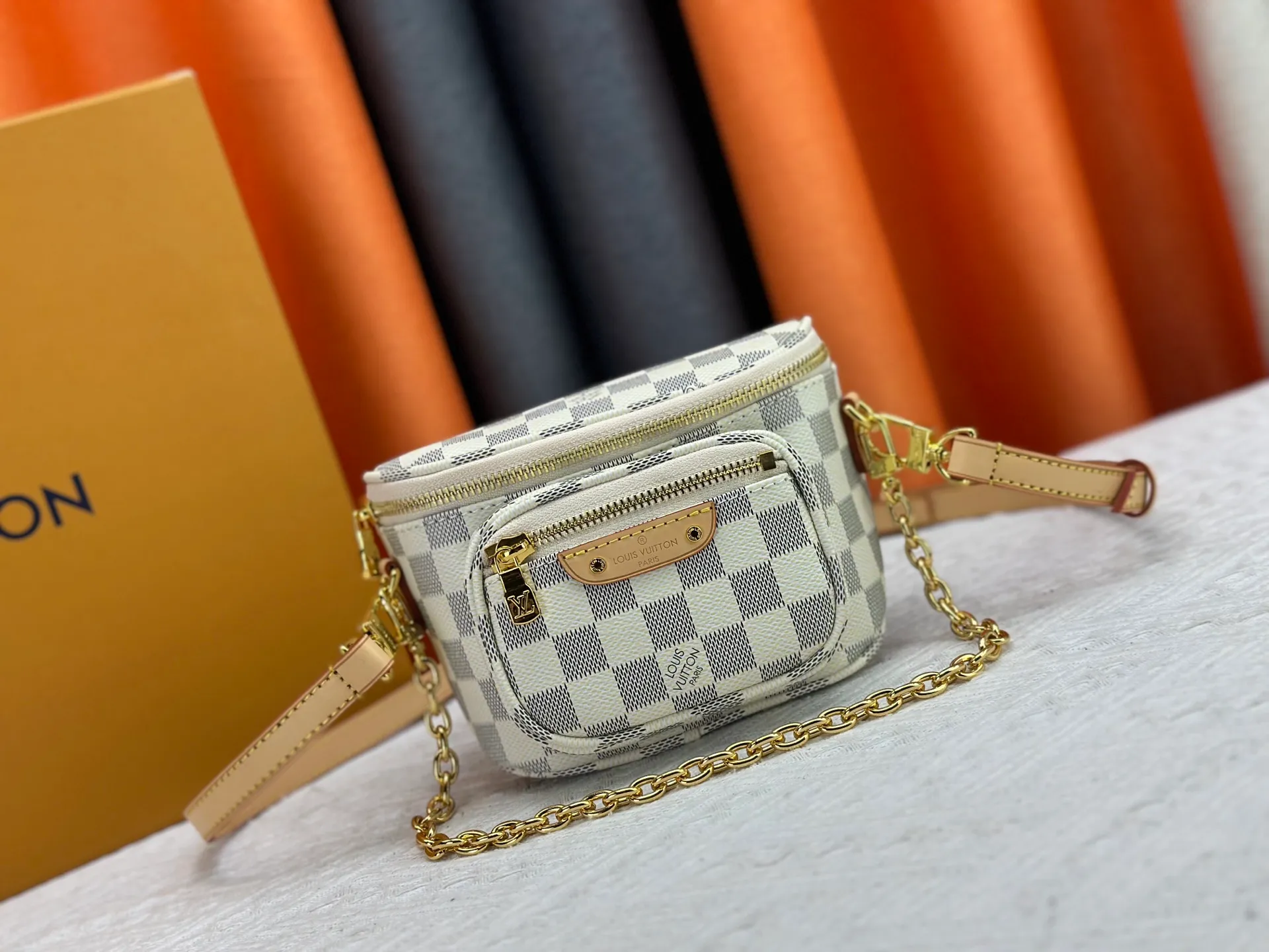 P240 M82208 M00130 M82335 This Mini Bumbag handbag comes from the LV Gradient series. The Monogram embossing of Monogram Empreinte leather renders the gradient midsummer color. The on-trend construction features a zipped main compartment and a front pocket with a Louis Vuitton leather label. With the detachable chain and detachable and adjustable shoulder strap, it can be worn as a shoulder or cross-body bag. Dimensions: 17x12x9.5 cm