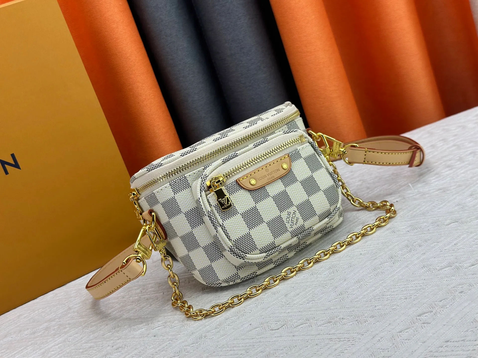 P240 M82208 M00130 M82335 This Mini Bumbag handbag comes from the LV Gradient series. The Monogram embossing of Monogram Empreinte leather renders the gradient midsummer color. The on-trend construction features a zipped main compartment and a front pocket with a Louis Vuitton leather label. With the detachable chain and detachable and adjustable shoulder strap, it can be worn as a shoulder or cross-body bag. Dimensions: 17x12x9.5 cm