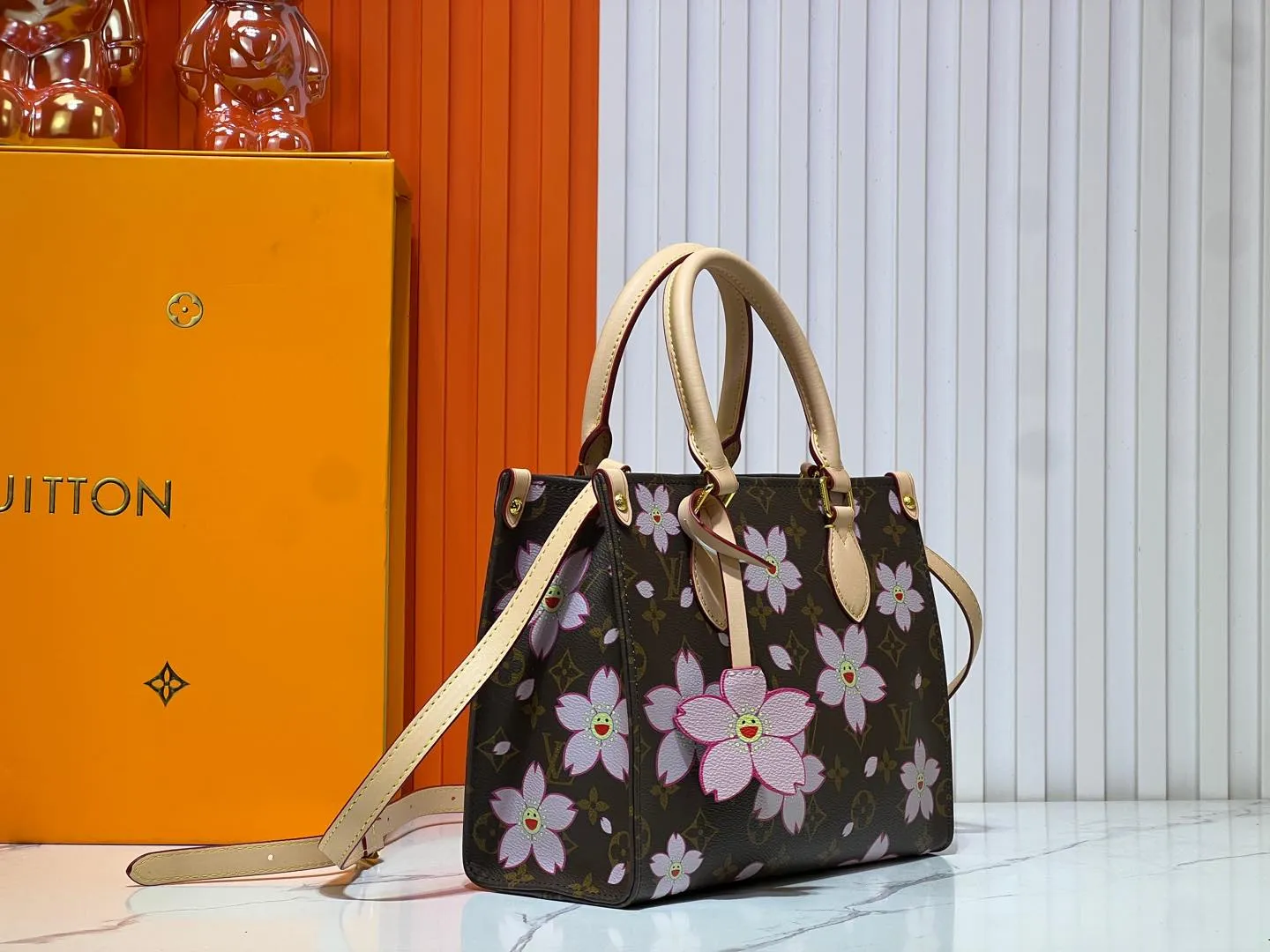 Batch 260💰M45659 M13668!🔥Lv&Takashi Murakami🐼Sakura🌸OnTheGo small new version The legendary ONTHEGO handbag: always able to meet your various needs for handbags. It has a large capacity but is not bulky. It is stiff and soft to the touch, making it suitable for home and travel. Tighten the side ties and it instantly transforms into a stylish urban handbag. Loosen the straps and it transforms into a chic and practical handbag. The slender leather handle can be carried over the shoulder or between the arms. The model shown here is made of Damier Azur canvas. Size: 25x11x19cm