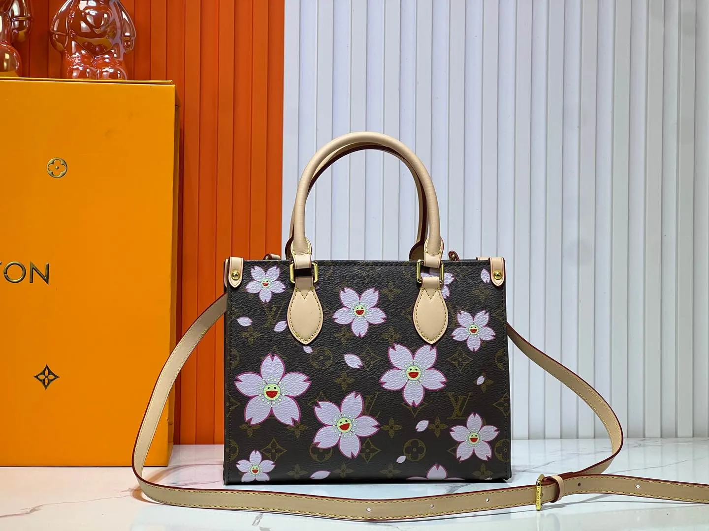 Batch 260💰M45659 M13668!🔥Lv&Takashi Murakami🐼Sakura🌸OnTheGo small new version The legendary ONTHEGO handbag: always able to meet your various needs for handbags. It has a large capacity but is not bulky. It is stiff and soft to the touch, making it suitable for home and travel. Tighten the side ties and it instantly transforms into a stylish urban handbag. Loosen the straps and it transforms into a chic and practical handbag. The slender leather handle can be carried over the shoulder or between the arms. The model shown here is made of Damier Azur canvas. Size: 25x11x19cm