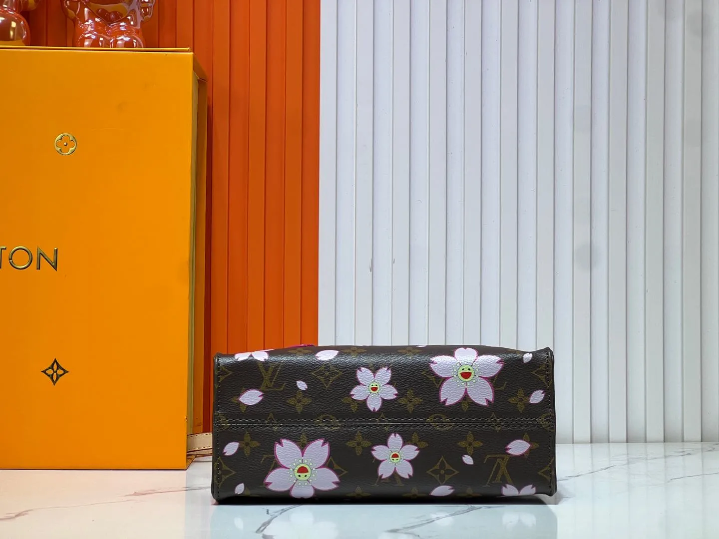 Batch 260💰M45659 M13668!🔥Lv&Takashi Murakami🐼Sakura🌸OnTheGo small new version The legendary ONTHEGO handbag: always able to meet your various needs for handbags. It has a large capacity but is not bulky. It is stiff and soft to the touch, making it suitable for home and travel. Tighten the side ties and it instantly transforms into a stylish urban handbag. Loosen the straps and it transforms into a chic and practical handbag. The slender leather handle can be carried over the shoulder or between the arms. The model shown here is made of Damier Azur canvas. Size: 25x11x19cm