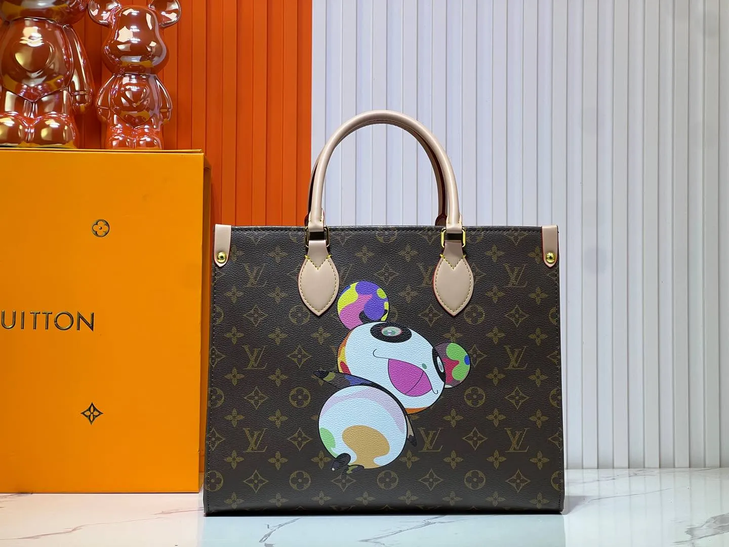 Batch 300💰M45039 M13668!🔥Lv&Takashi Murakami🐼Panda print OnTheGo new version The legendary ONTHEGO handbag: always able to meet your various needs for handbags. It has a large capacity but is not bulky. It is stiff and soft to the touch, making it suitable for home and travel. Tighten the side ties and it instantly transforms into a stylish urban handbag. Loosen the straps and it transforms into a chic and practical handbag. The slender leather handle can be carried over the shoulder or between the arms. The model shown here is made of Damier Azur canvas. Size: 35x27x14cm