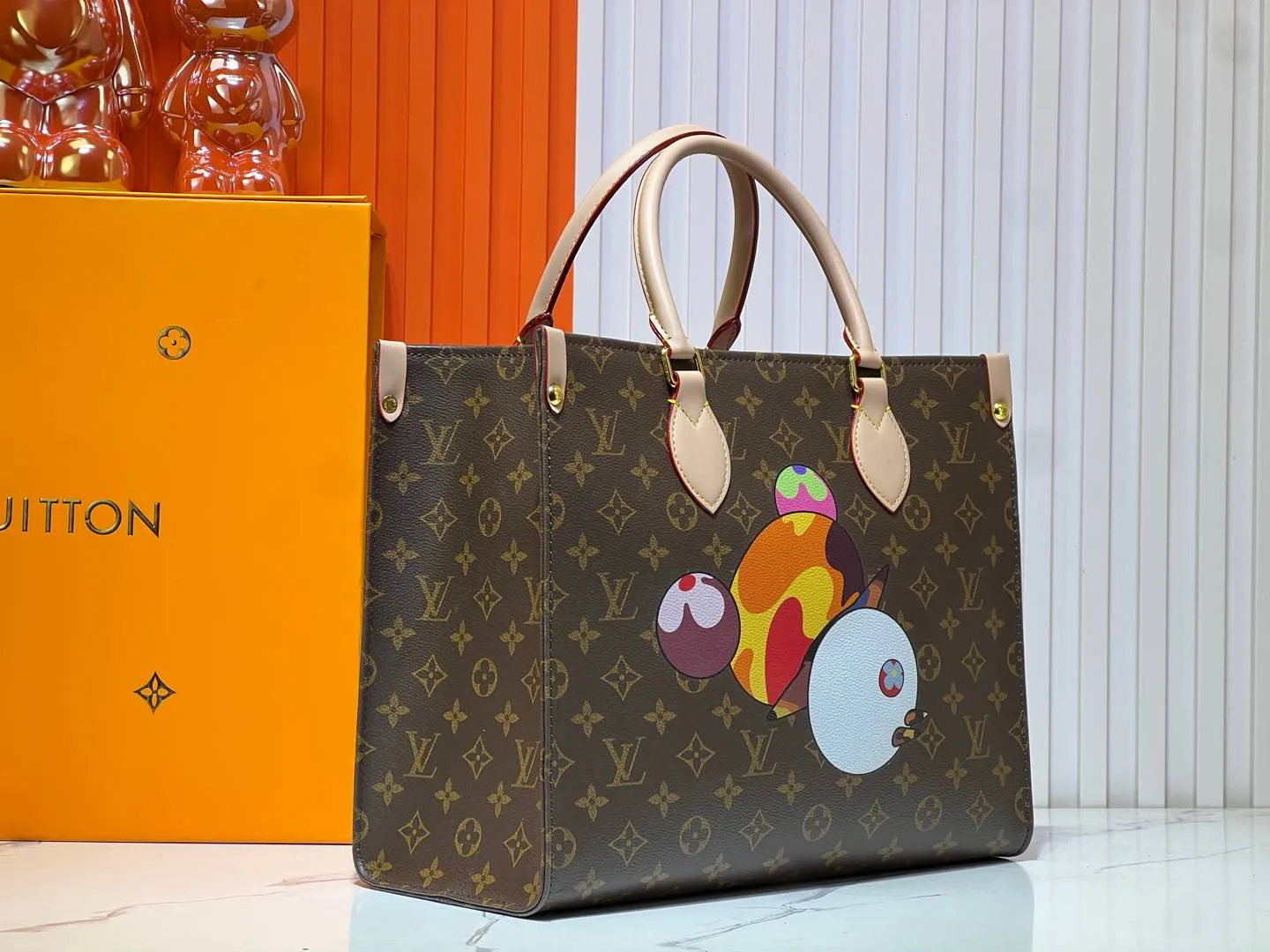 Batch 300💰M45039 M13668!🔥Lv&Takashi Murakami🐼Panda print OnTheGo new version The legendary ONTHEGO handbag: always able to meet your various needs for handbags. It has a large capacity but is not bulky. It is stiff and soft to the touch, making it suitable for home and travel. Tighten the side ties and it instantly transforms into a stylish urban handbag. Loosen the straps and it transforms into a chic and practical handbag. The slender leather handle can be carried over the shoulder or between the arms. The model shown here is made of Damier Azur canvas. Size: 35x27x14cm