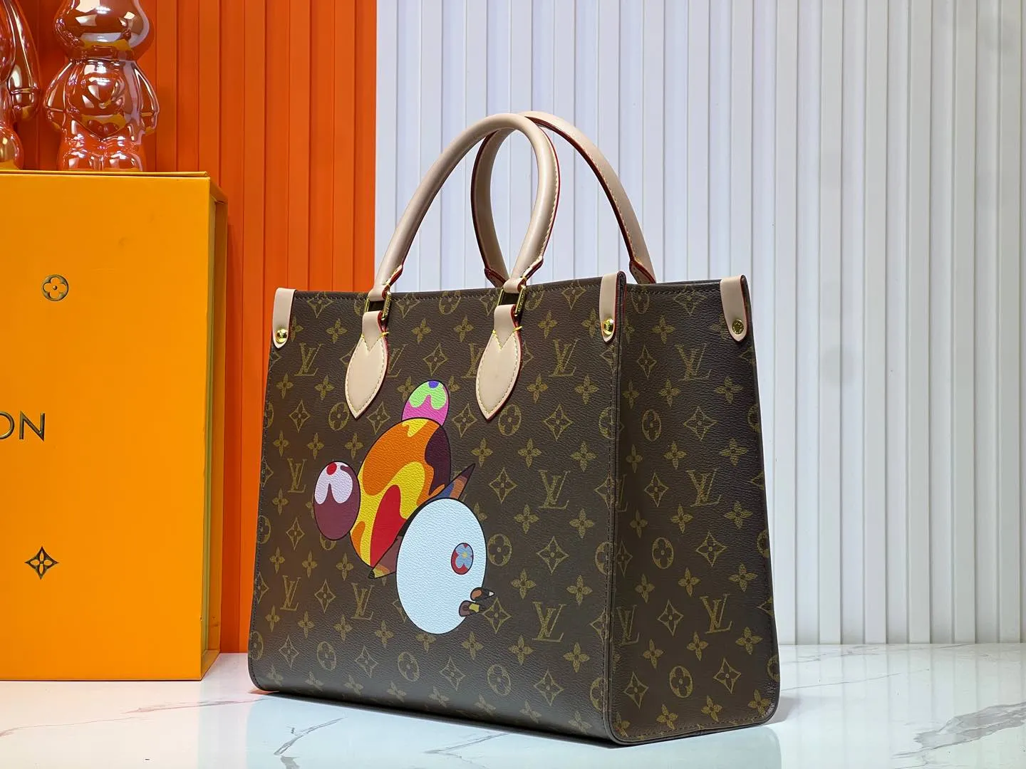 Batch 300💰M45039 M13668!🔥Lv&Takashi Murakami🐼Panda print OnTheGo new version The legendary ONTHEGO handbag: always able to meet your various needs for handbags. It has a large capacity but is not bulky. It is stiff and soft to the touch, making it suitable for home and travel. Tighten the side ties and it instantly transforms into a stylish urban handbag. Loosen the straps and it transforms into a chic and practical handbag. The slender leather handle can be carried over the shoulder or between the arms. The model shown here is made of Damier Azur canvas. Size: 35x27x14cm