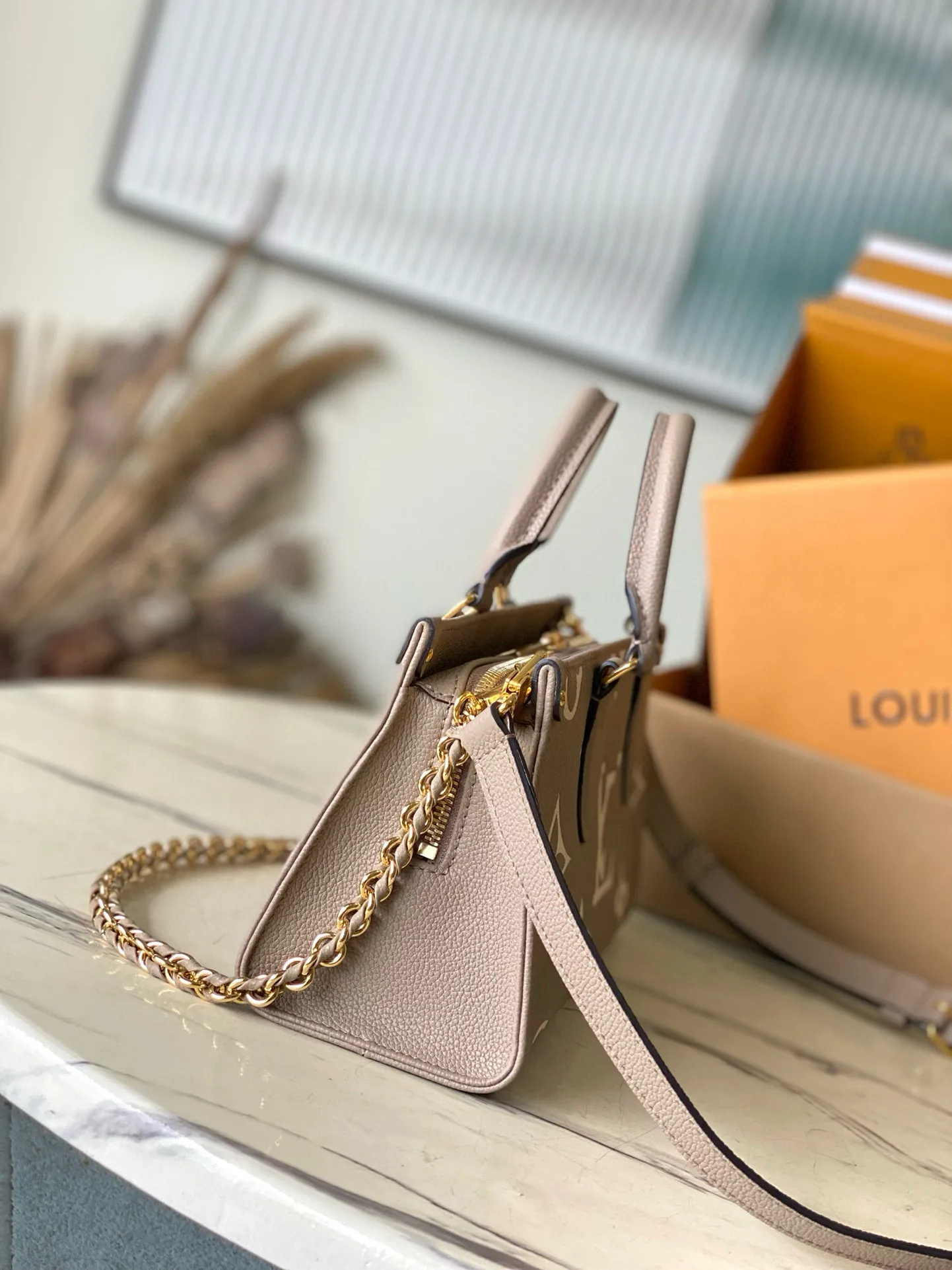 💰1100 (top layer leather) top original order M23641 Elephant Gray This small OnTheGo handbag is Monogram Empreinte leather embossed with the Giant Monogram pattern, highlighting the soft and slender silhouette. The compact interior keeps your daily essentials organized, while the articulated top handle and detachable leather and woven chain shoulder strap allow for a variety of carrying options. Dimensions: 25 × 13 × 10 cm