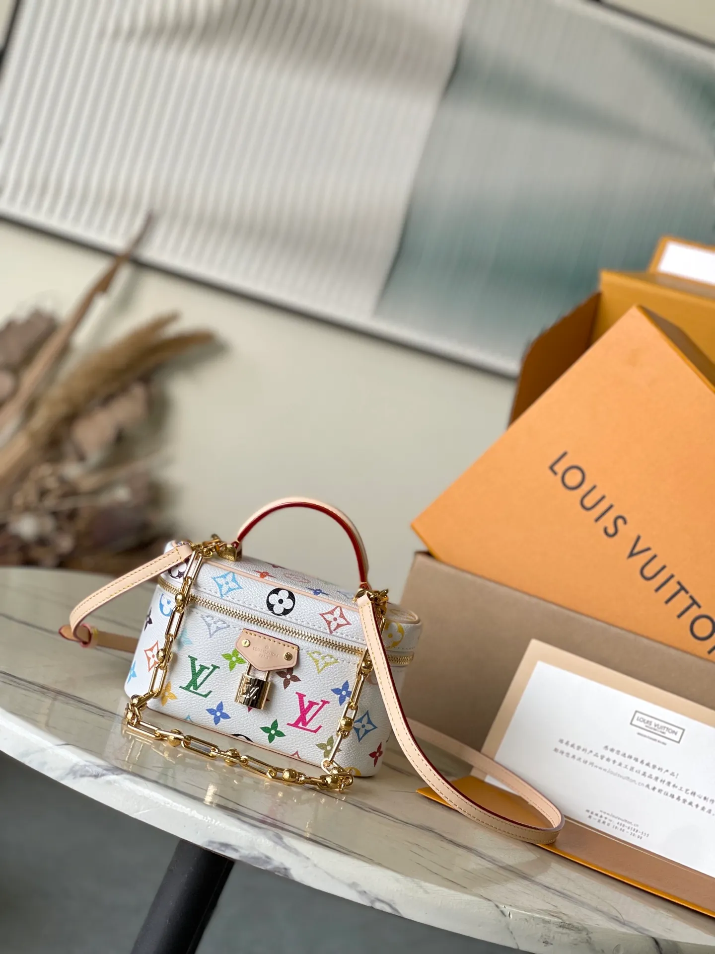 💰900 Top Original Order M13662 This Vanity Pouch handbag is from the Louis Vuitton x Murakami reissue series, reinterpreting the brand's classic Monogram pattern with the artist's bright tones. The coated canvas is trimmed with cow leather, and the zipper closure, detachable chain and LV-engraved padlock add a metallic sheen. Dimensions: 19 × 11.5 × 6.5 cm