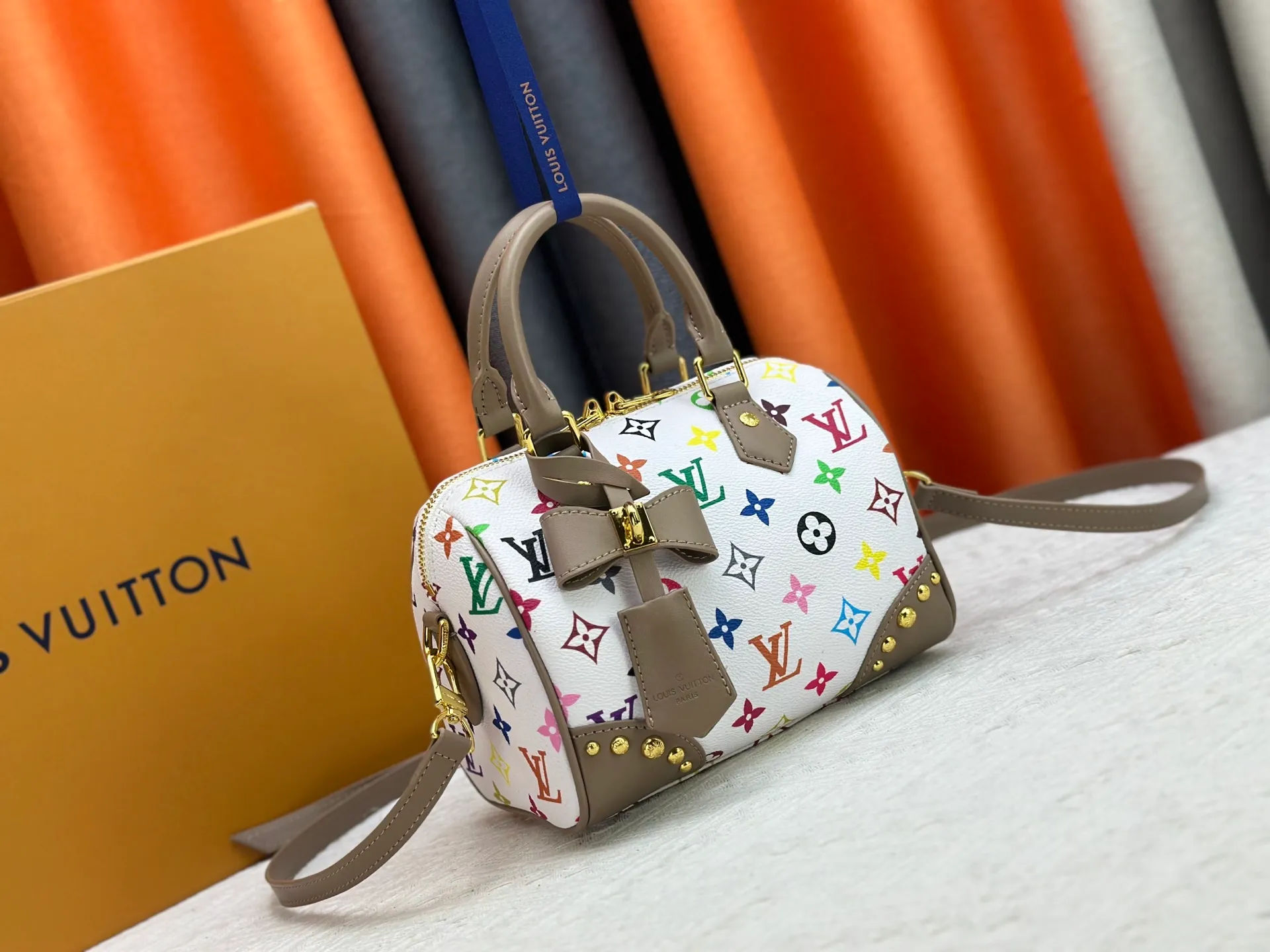 P260 upgraded original M58953 M46234 M46222 Speedy Bandoulière 20 handbag is made of soft coated canvas, and the full-length Monogram pattern is traced in colorful rainbow tones, highlighting the smart style of the Louis Vuitton x Murakami reissue series. The Toron handle and detachable shoulder strap are constructed of cow leather, the metal corners recall classic luggage elements, and the bow-shaped key bag and padlock add brand touches. Dimensions: 20.5 x 13.5 x 12.0 cm (length x height x width)