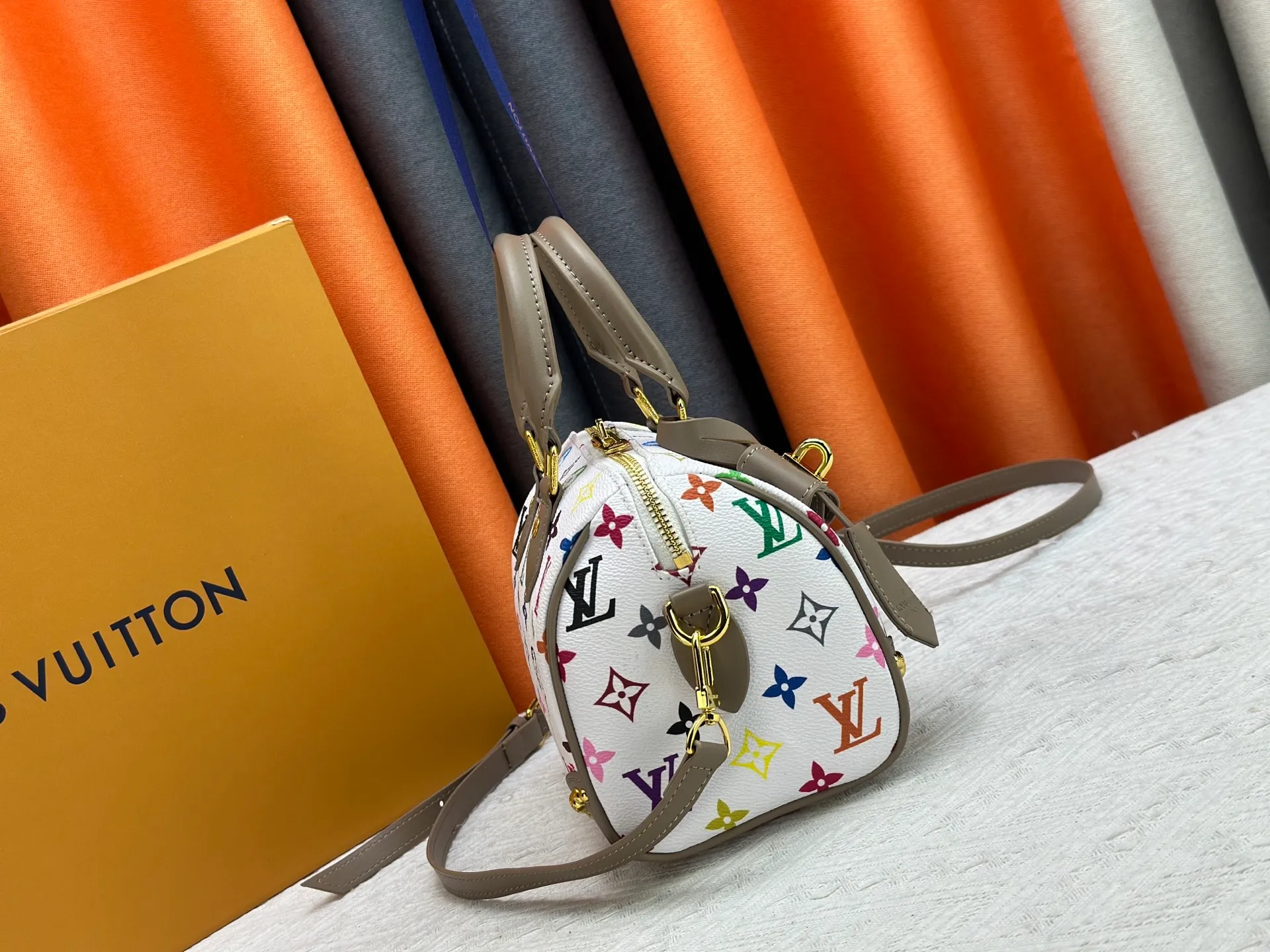 P260 upgraded original M58953 M46234 M46222 Speedy Bandoulière 20 handbag is made of soft coated canvas, and the full-length Monogram pattern is traced in colorful rainbow tones, highlighting the smart style of the Louis Vuitton x Murakami reissue series. The Toron handle and detachable shoulder strap are constructed of cow leather, the metal corners recall classic luggage elements, and the bow-shaped key bag and padlock add brand touches. Dimensions: 20.5 x 13.5 x 12.0 cm (length x height x width)
