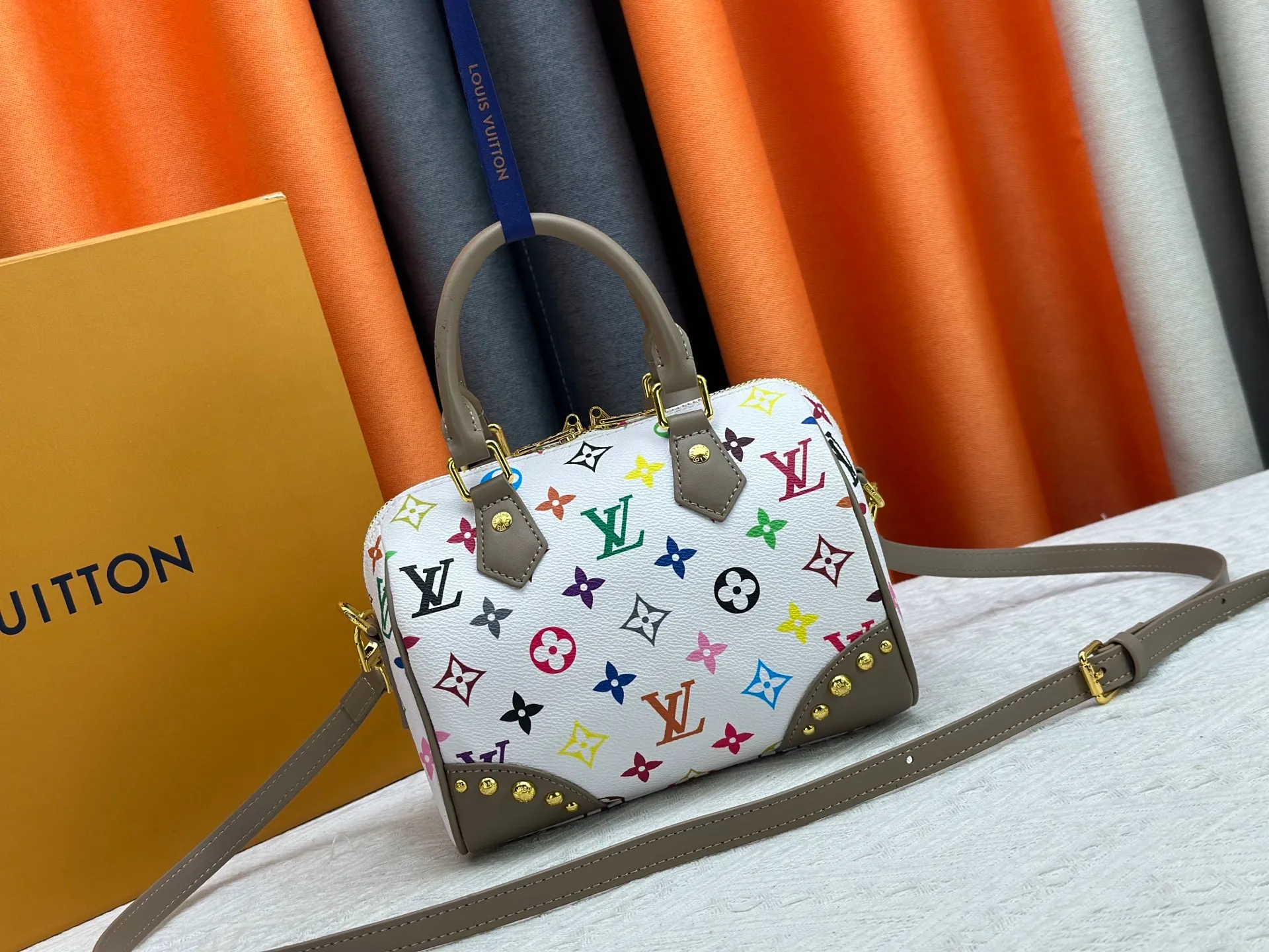 P260 upgraded original M58953 M46234 M46222 Speedy Bandoulière 20 handbag is made of soft coated canvas, and the full-length Monogram pattern is traced in colorful rainbow tones, highlighting the smart style of the Louis Vuitton x Murakami reissue series. The Toron handle and detachable shoulder strap are constructed of cow leather, the metal corners recall classic luggage elements, and the bow-shaped key bag and padlock add brand touches. Dimensions: 20.5 x 13.5 x 12.0 cm (length x height x width)
