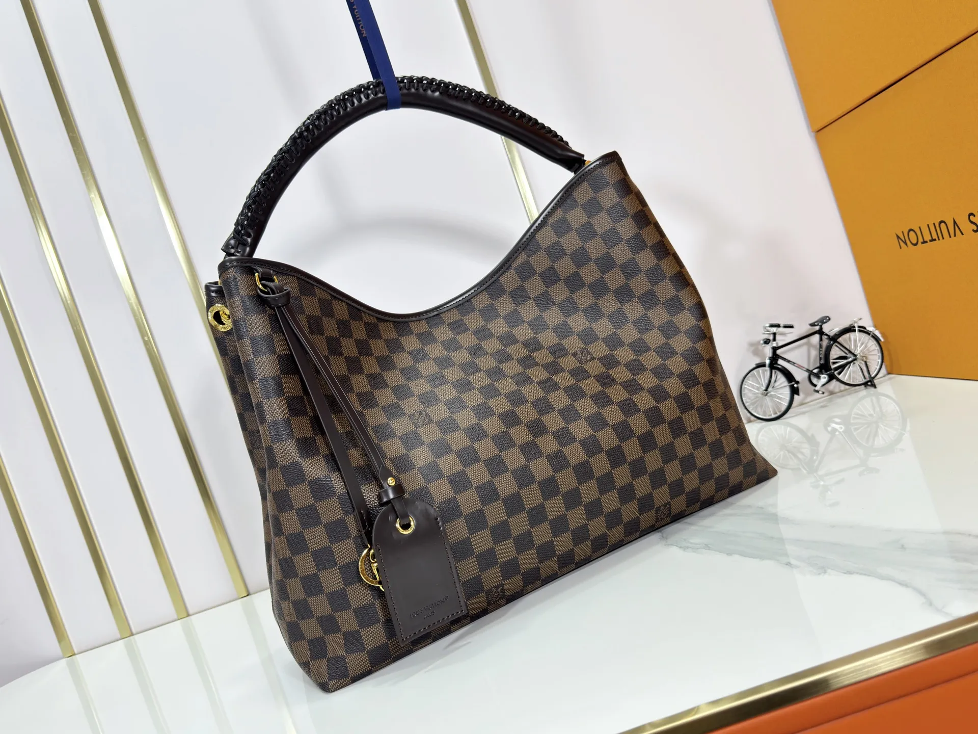 P280 upgrades the original M25877 Again handbag, a new interpretation of the iconic Artsy design first launched in 2010, now more flexible, more iconic and more refined. Rooted in LV’s DNA, this bag pays homage to Louis Vuitton’s craftsmanship with its classic Monogram canvas base, hand-woven handles and customizable name tag. It's spacious enough to hold a laptop and opens to reveal multiple pockets. Gold hooks can be used to hang playful accessories! ! Size:50x30x15.5CM
