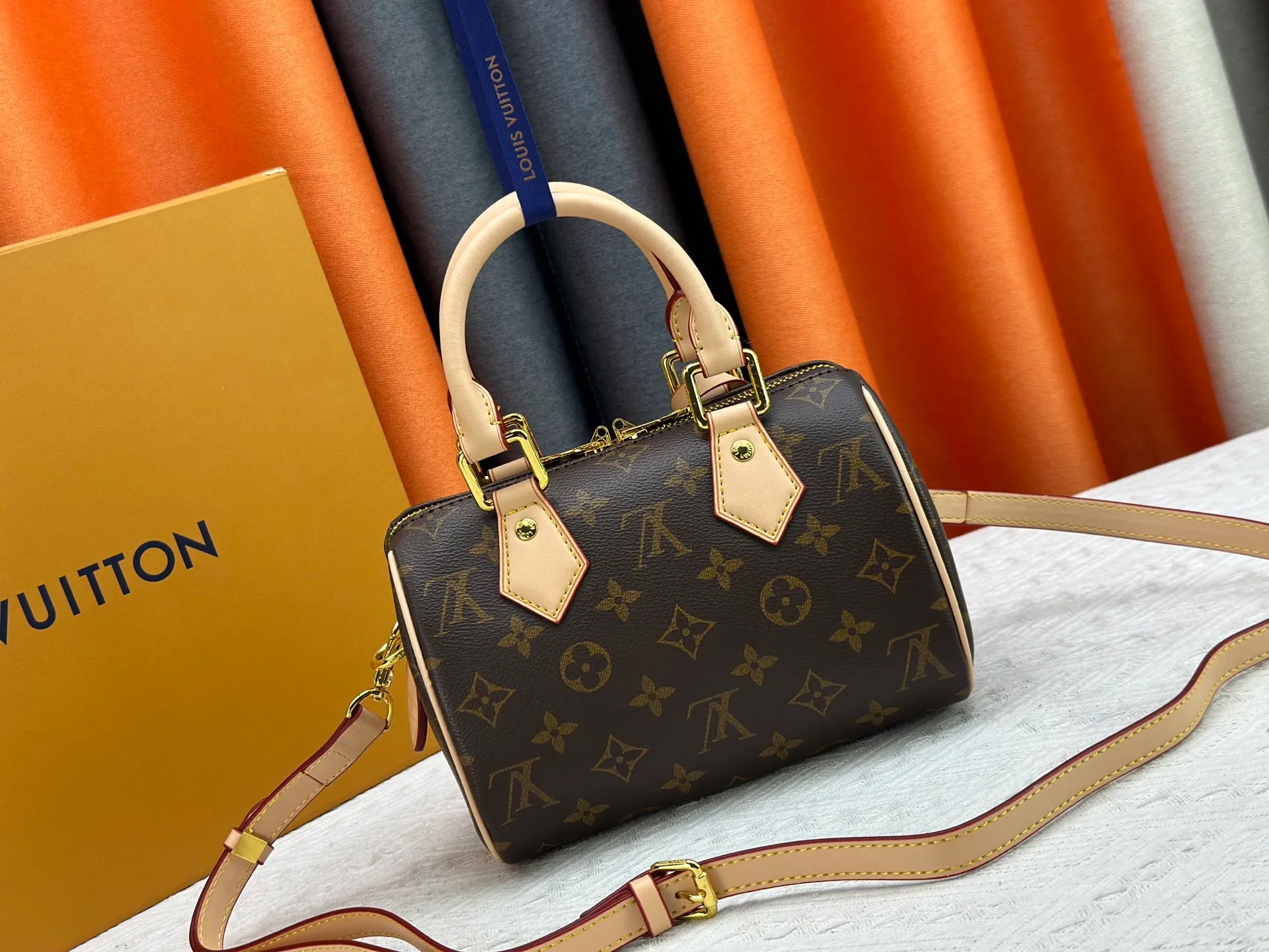 P260 Upgraded from the original version, this M46234 M46222 Speedy Bandoulière 20 handbag is made of soft coated canvas, with the full-length Monogram pattern traced in colorful rainbow tones, highlighting the smart style of the Louis Vuitton x Murakami reissue series. The Toron handle and detachable shoulder strap are constructed of cow leather, the metal corners recall classic luggage elements, and the bow-shaped key bag and padlock add brand touches. Dimensions: 20.5 x 13.5 x 12.0 cm (length x height x width)