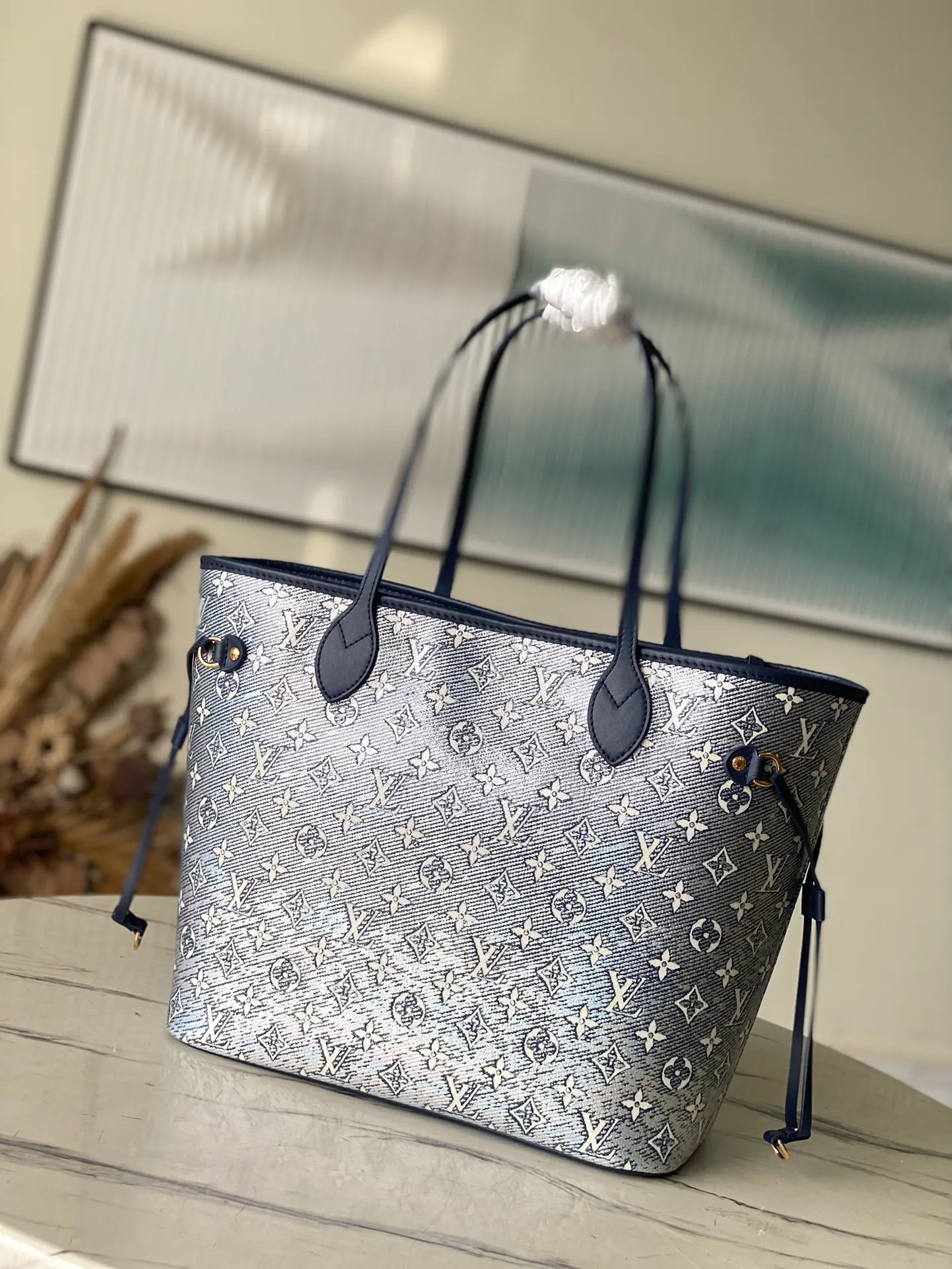 💰1140 Top Original M22921 This Neverfull medium handbag is made of Monoglam coated canvas to create an eye-catching holographic effect. The canvas is made from a jacquard base fabric woven with cotton and decorative threads, and has a reflective coating that changes colors under the light. The slim handle allows for comfortable shoulder and elbow carry. size：31x28x14cm