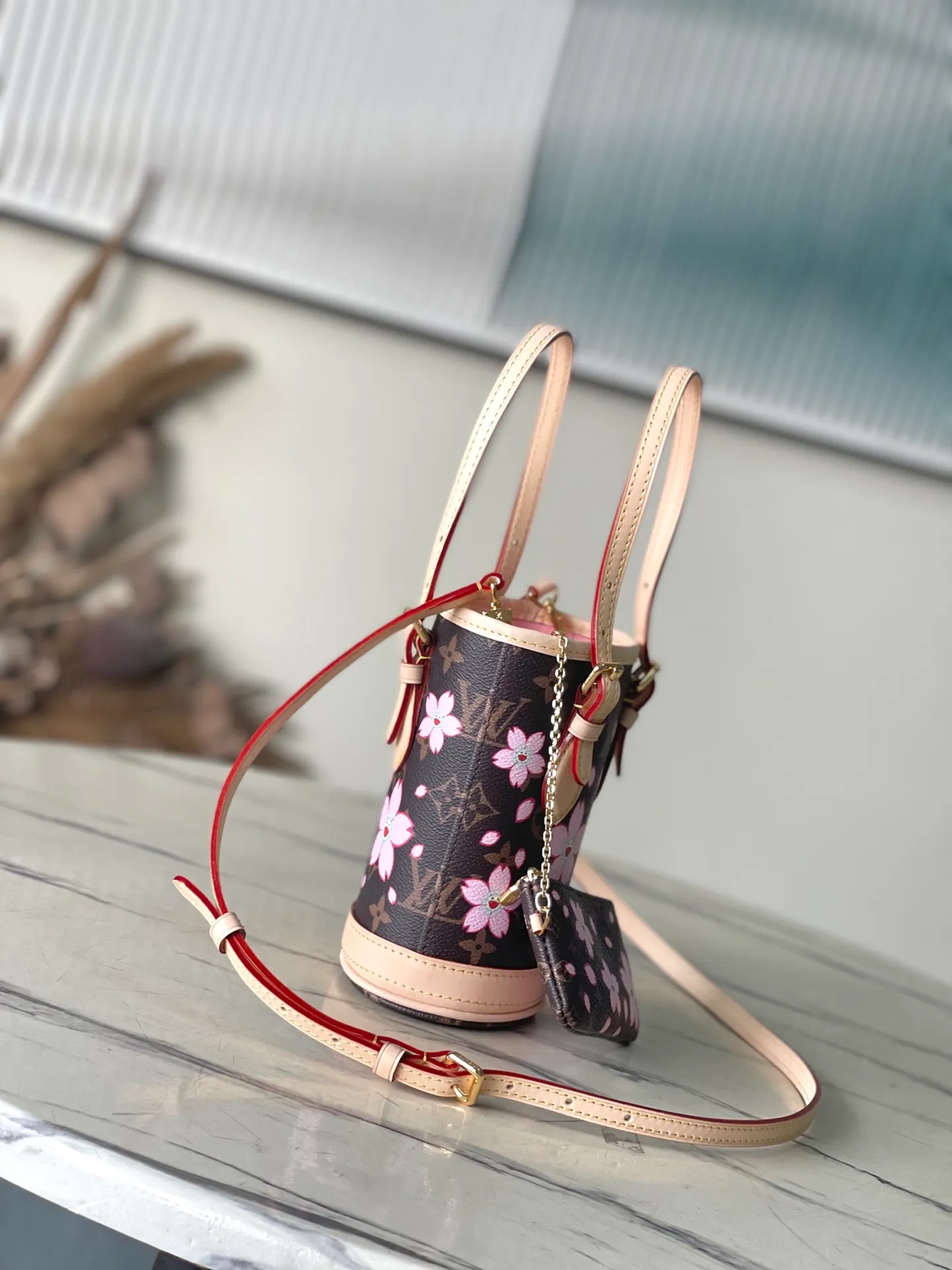 💰960 Top Original Order M13417 This Nano Bucket handbag is constructed of classic Monogram coated canvas with a sophisticated design, and is completed with cow leather trim and dazzling metal parts. The Cherry Blossom pattern on the body of the bag conveys the atmosphere of prosperous recovery and highlights the distinctive style of Japanese artist Takashi Murakami. The detachable shoulder strap allows for a variety of carrying options, and the leather keychain adds a functional detail. Dimensions: 13 × 17 × 9 cm