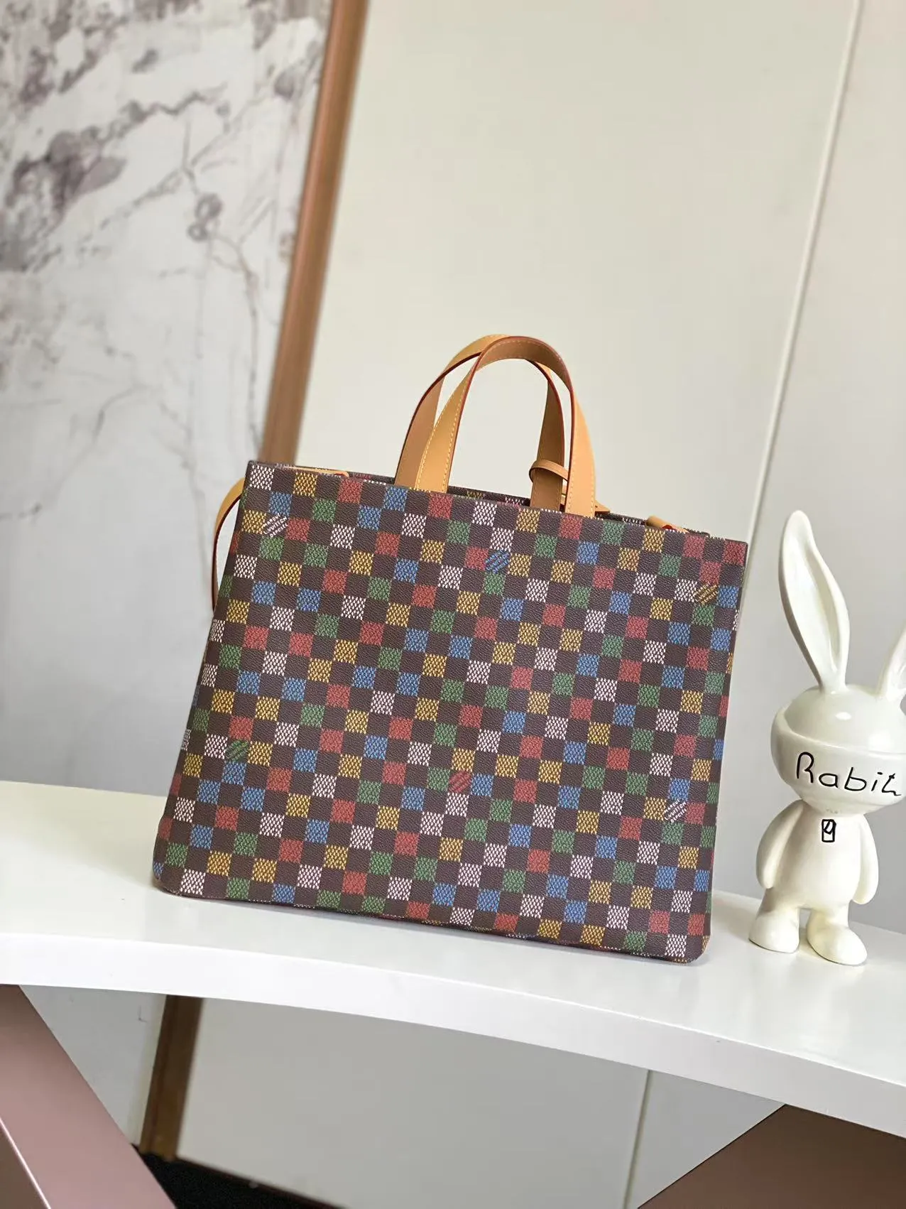 💰1100 Top Original N00192 Shopper Tote handbag design is inspired by Louis Vuitton's classic shopping bag, characterized by the same clean lines and contrasting Louis Vuitton letter logo. Crafted from LVers Damier Ebene coated canvas, this bag features Pharrell Williams' colorful reinterpretation of the Damier pattern (inspired by a classic design created by Georges Vuitton in 1888). Two top handles and a detachable shoulder strap provide a flexible carrying method that combines practicality with unique charm. Dimensions: 32 x 16 x 40 cm