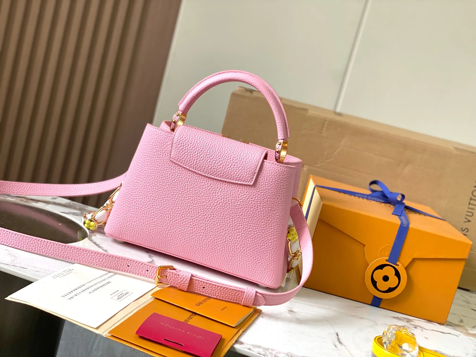 p2600 [Super high-quality original leather💋 M23280 pink and white shell buckle upgraded hardware] [Capucines BB handbag] This season’s new Capucines BB handbag highlights femininity. Metal links and elegant soft cow leather are woven into a delicate chain, with enamel and Monogram flowers scattered on it. The enamel brand logo highlights the texture of jewelry and makes the handbag even more beautiful.  Dimensions: 27 x 18 x 9 cm