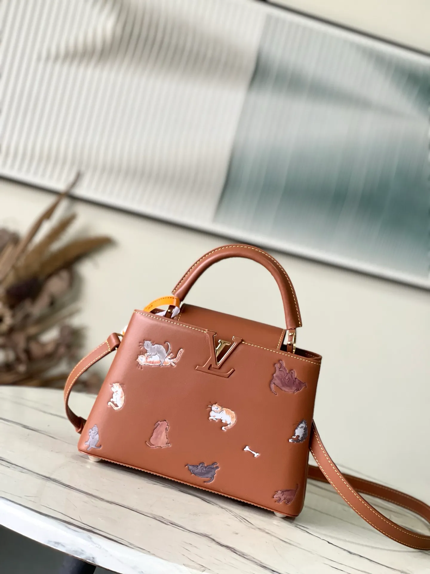 💰2400 "Special Original Leather" M25874 Small LV Travels With series renders the Capucines BB handbag in classic colors, adding smart details with cat illustrations hand-drawn by fashion icon and artist Grace Coddington. This replica is derived from the first collaboration in 2019 and features a cowhide body with LV letters. The flip cover can be folded in or out, and the detachable long shoulder strap allows for a variety of carrying methods. 27x17.3x9cm