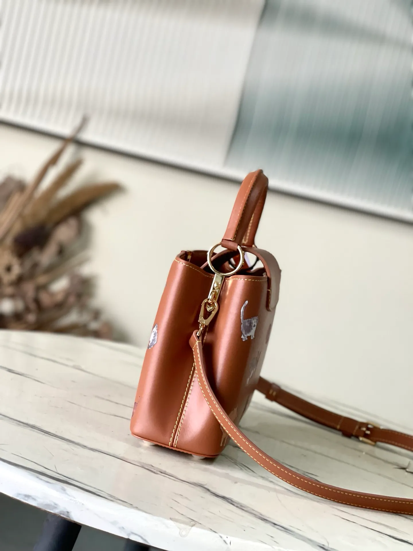💰2400 "Special Original Leather" M25874 Small LV Travels With series renders the Capucines BB handbag in classic colors, adding smart details with cat illustrations hand-drawn by fashion icon and artist Grace Coddington. This replica is derived from the first collaboration in 2019 and features a cowhide body with LV letters. The flip cover can be folded in or out, and the detachable long shoulder strap allows for a variety of carrying methods. 27x17.3x9cm
