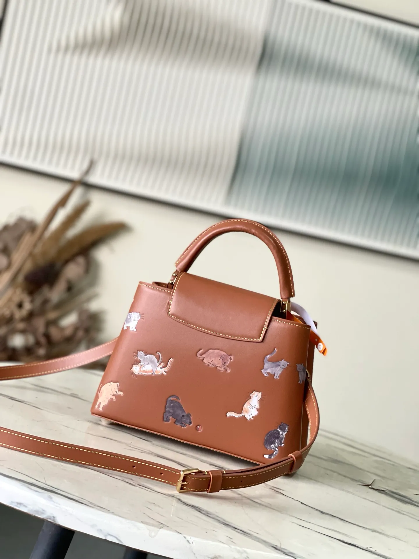 💰2400 "Special Original Leather" M25874 Small LV Travels With series renders the Capucines BB handbag in classic colors, adding smart details with cat illustrations hand-drawn by fashion icon and artist Grace Coddington. This replica is derived from the first collaboration in 2019 and features a cowhide body with LV letters. The flip cover can be folded in or out, and the detachable long shoulder strap allows for a variety of carrying methods. 27x17.3x9cm