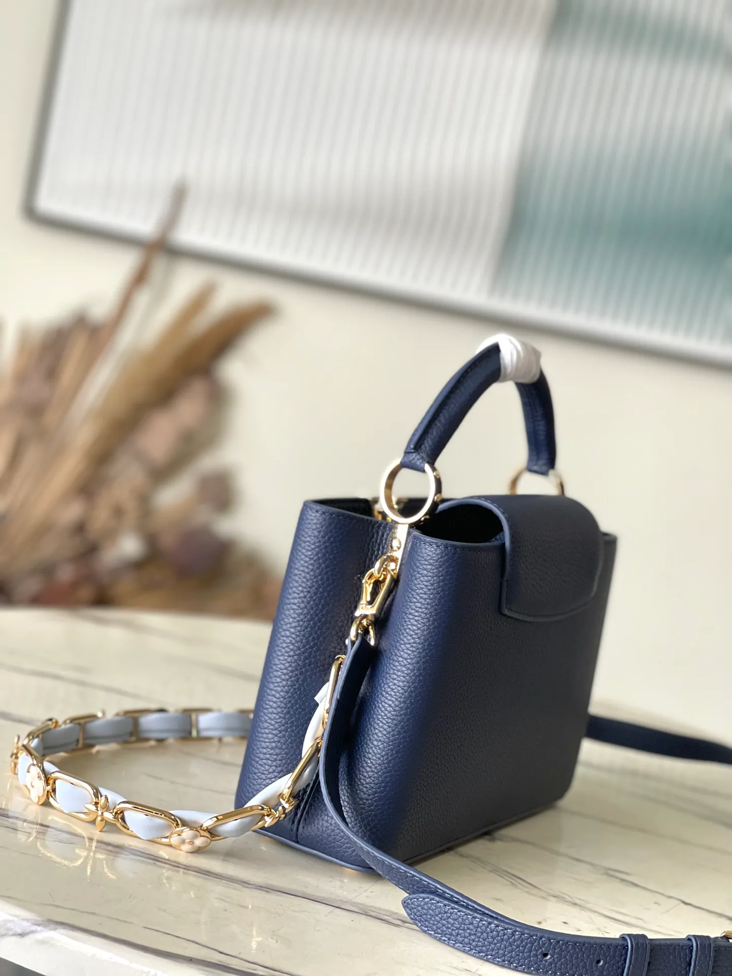 💰2400 (Special grade original leather) M23199 Blue Small This elegant Capucines small handbag combination is matched with a variety of materials and textures, made of aurilon leather, and equipped with a beautiful new version of Blossom Chain. Metal links and elegant soft cow leather are woven into a delicate chain, inlaid with Swiss enamel and veneer Monogram flowers. The colorful enamel brand logo highlights the texture of jewelry and makes the handbag even more beautiful. Dimensions: 27 × 18 × 9 cm