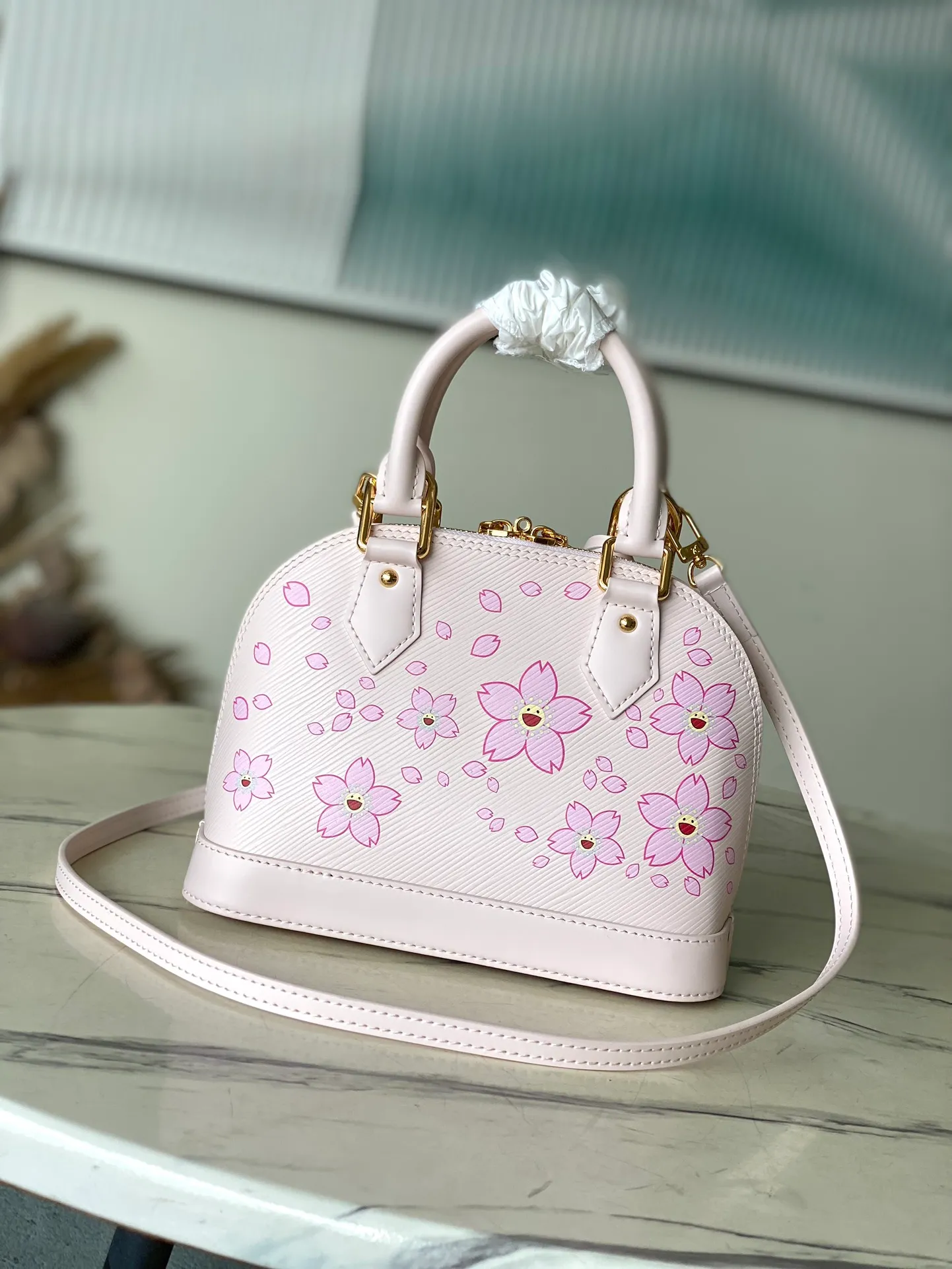 💰1400 Top original order M13104 (M40302 Sakura) Maison’s iconic Alma BB bag is now modified into a playful cherry blossom pattern, which is the creation of artist Takashi Murakami, symbolizing innovation. The design is sewn from Epi leather, veined in an elegant pink color, combined with shiny yellow metallic details. There is room inside to enlarge daily necessities such as mobile phones. Toron handles and an easily removable leather strap complete the overall luxury feel.  23.5 x 17.5 x 11.5 cm (LxHxW)