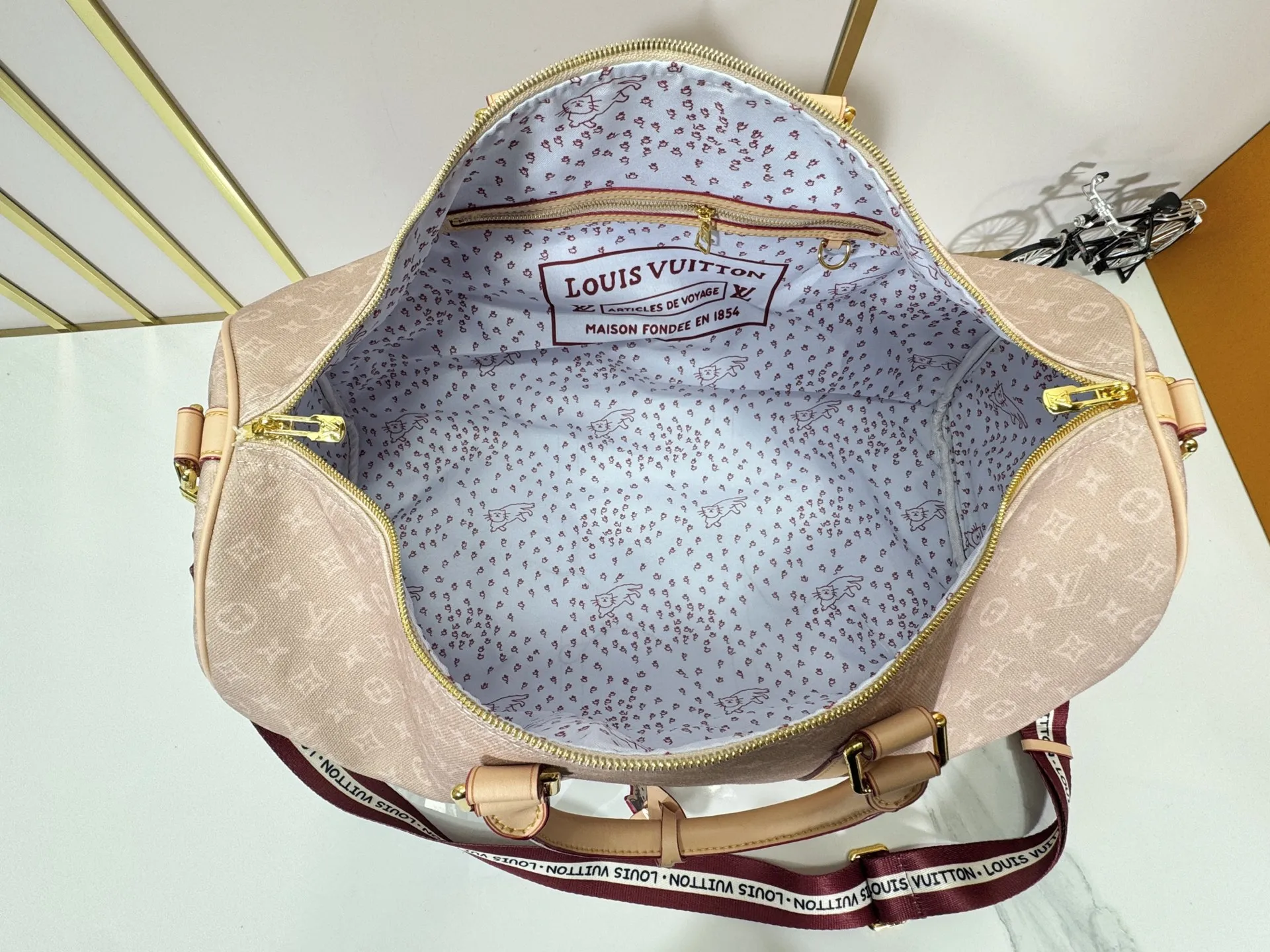 P360 M25787 M41416 This Keepall Bandouliere 50 travel bag is from the Travel With series presented by Louis Vuitton in collaboration with Grace Coddington. It uses Meowgram canvas to interpret the Monogram pattern in a playful way, looking back to the hard suitcase inspiration of the 1900s. The cute cat-shaped branding adds smart touches, and the detachable and adjustable shoulder strap is embellished with the handwritten brand logo. Size: 50x29x23cm