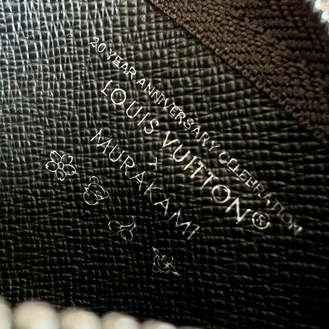 Factory price 280 Top original order M13664 black color This replica Louis Vuitton x Murakami series key coin purse is colorful and made of coated canvas. The vibrant iconic Monogram pattern reinterprets the brand logo with the theme of Japanese artist Takashi Murakami in rainbow tones. The key coin purse has a silver zipper and is equipped with a chain strap and hook buckle to store keys securely. 12 x 7 x 1.5 cm (length x height x width)