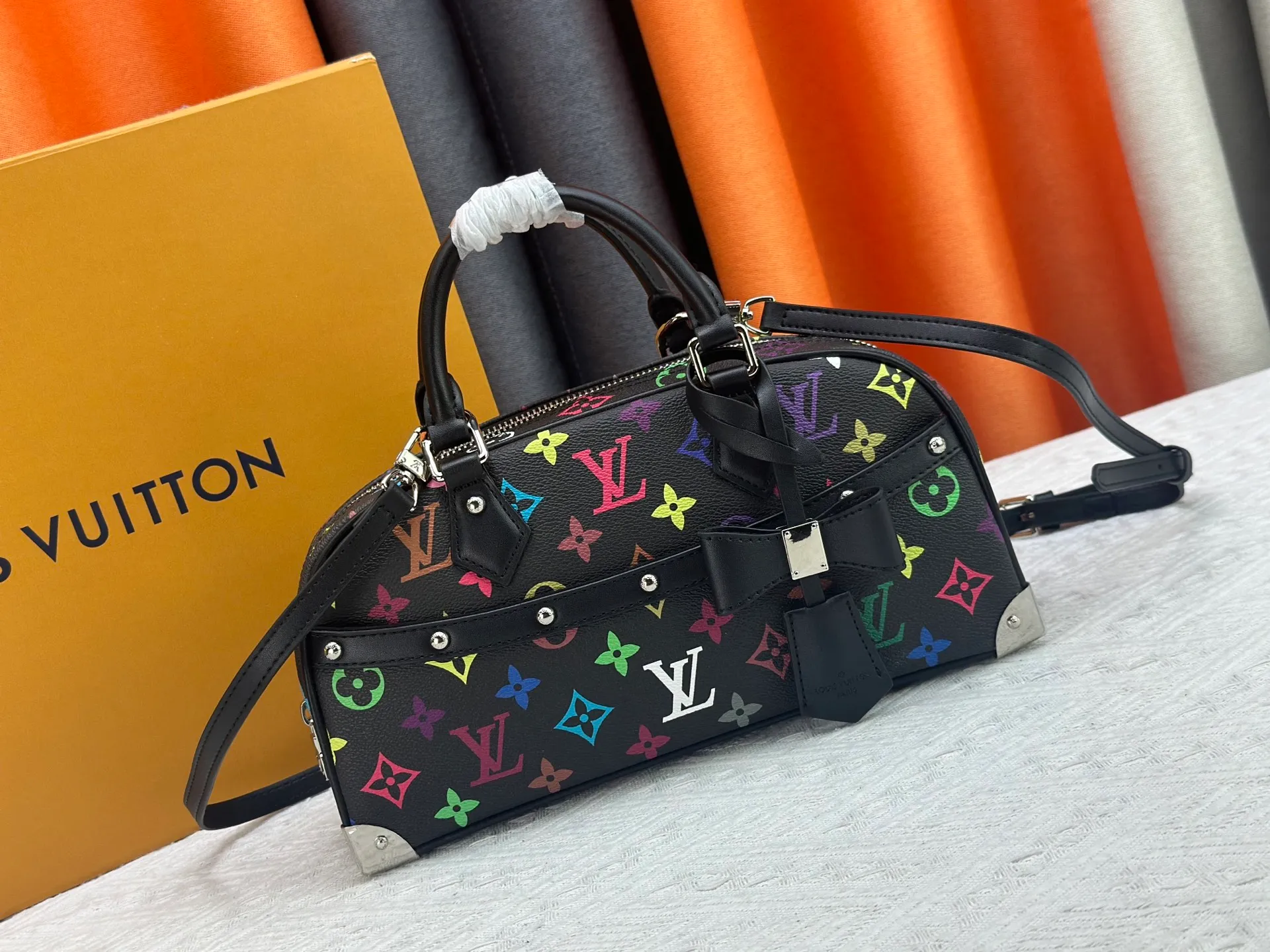 P280 Upgraded Original M13084 This Handbag East West handbag is from the Louis Vuitton x Takashi Murakami reissue series, using the artist's signature rainbow tones to trace the full-length Monogram pattern. Sleek horizontal construction lines the top handle, studded side straps, detachable and adjustable shoulder strap and LV x TM key holder, with cowhide leather details and sophisticated corners that nod to the brand's traditional luggage. Dimensions: 27.0 x 14.0 x 10.0 cm (length x height x width)