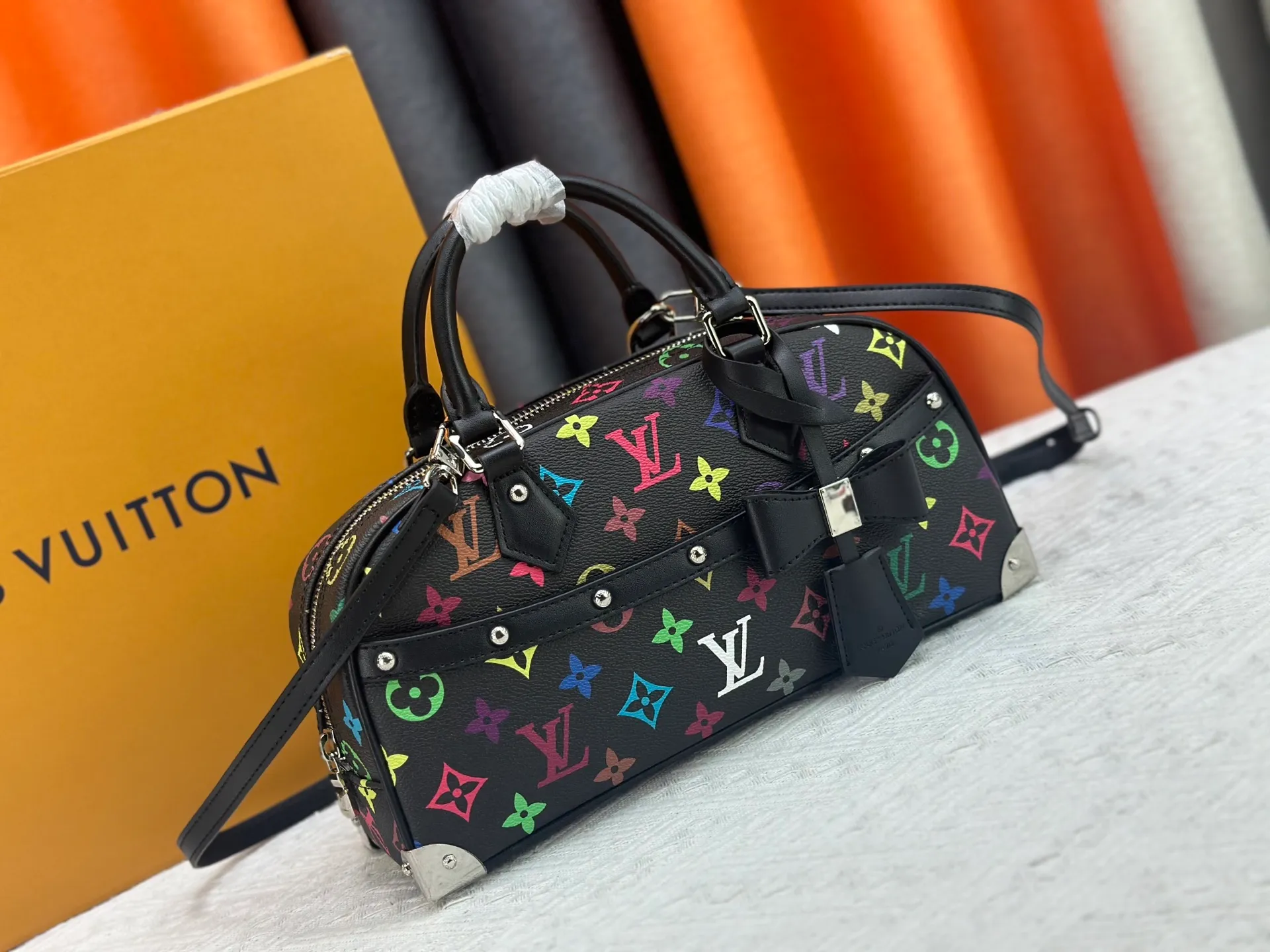 P280 Upgraded Original M13084 This Handbag East West handbag is from the Louis Vuitton x Takashi Murakami reissue series, using the artist's signature rainbow tones to trace the full-length Monogram pattern. Sleek horizontal construction lines the top handle, studded side straps, detachable and adjustable shoulder strap and LV x TM key holder, with cowhide leather details and sophisticated corners that nod to the brand's traditional luggage. Dimensions: 27.0 x 14.0 x 10.0 cm (length x height x width)