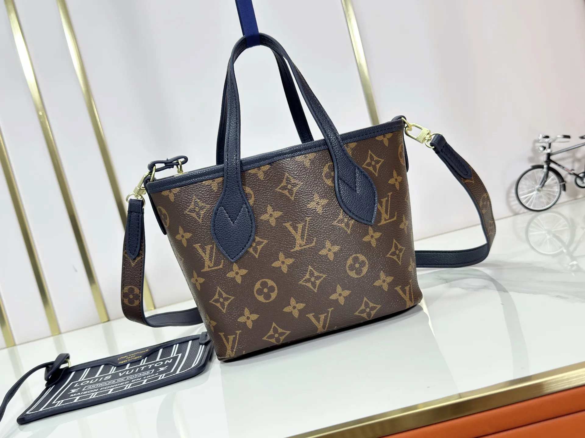 P220 M12099 Upgraded original Neverfull Bandouliere Inside Out BB handbag is a double-sided version of the classic design this season, with the front and back decorated with iconic Monogram canvas and grained leather. The removable zipper bag can be used alone or hung externally. The detachable shoulder strap makes it easy to wear cross-body, and the dazzling metal hardware adds a sophisticated detail. Dimensions: 24 × 14 × 9 cm