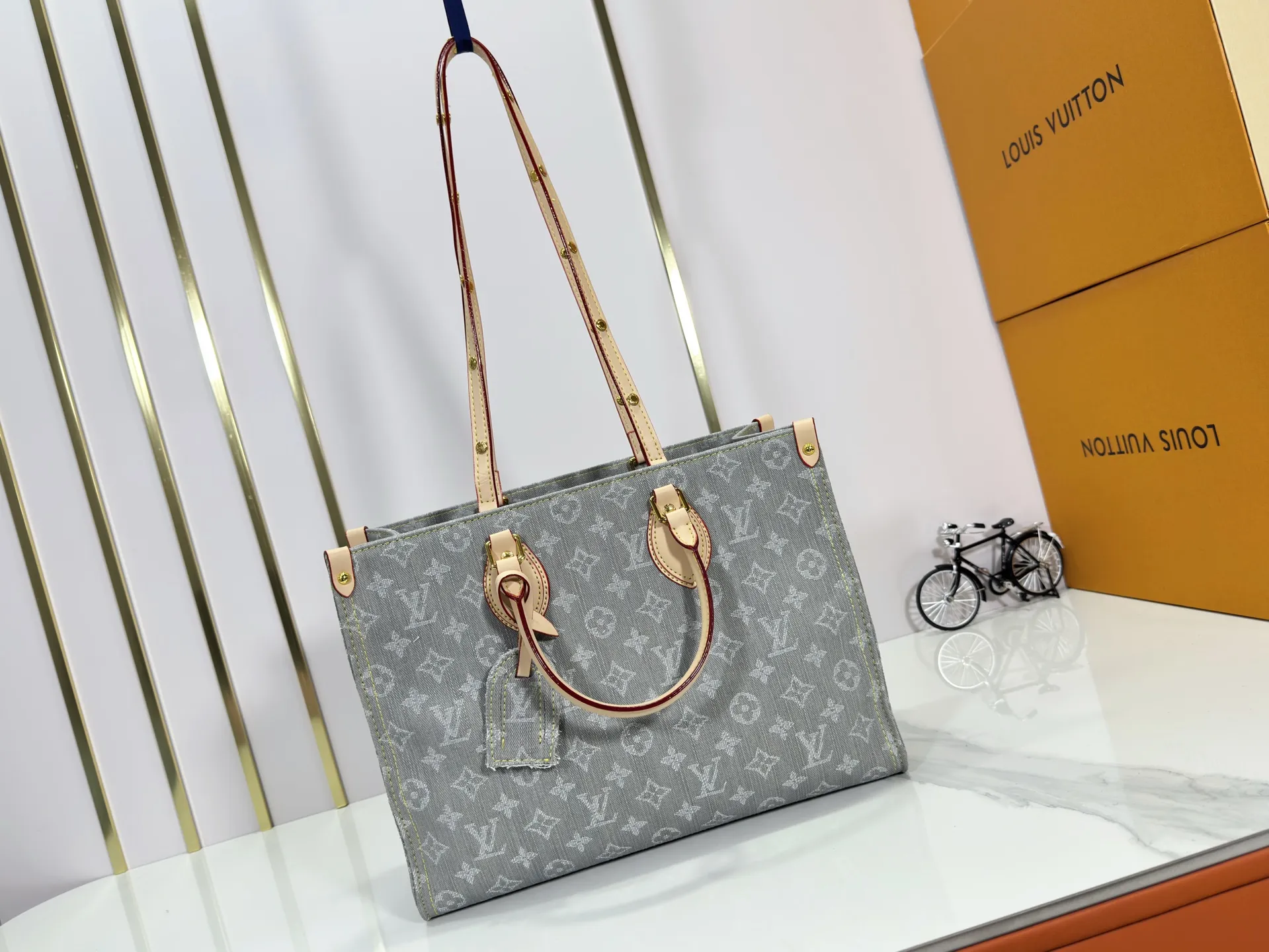 P320 M49495 M45659 M13189 New Gray Denim Denim This edition of OnTheGo MM celebrates the return of the iconic Monogram denim pattern in 2005. It's made from organic cotton, artfully woven with black and white threads and then bleached using a special Louis Vuitton technique to create a vintage-inspired finish. It's sized to hold a laptop, features light gold hardware, and includes signature details like natural leather accents and a removable name tag. Dimensions: 35 x 27 x 14 cm