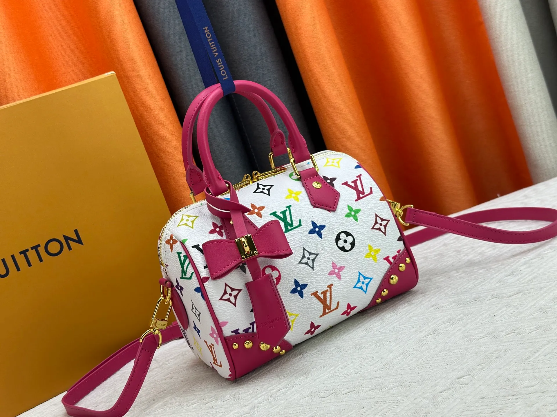 P260 upgraded original M58953 M46234 M46222 Speedy Bandoulière 20 handbag is made of soft coated canvas, and the full-length Monogram pattern is traced in colorful rainbow tones, highlighting the smart style of the Louis Vuitton x Murakami reissue series. The Toron handle and detachable shoulder strap are constructed of cow leather, the metal corners recall classic luggage elements, and the bow-shaped key bag and padlock add brand touches. Dimensions: 20.5 x 13.5 x 12.0 cm (length x height x width)