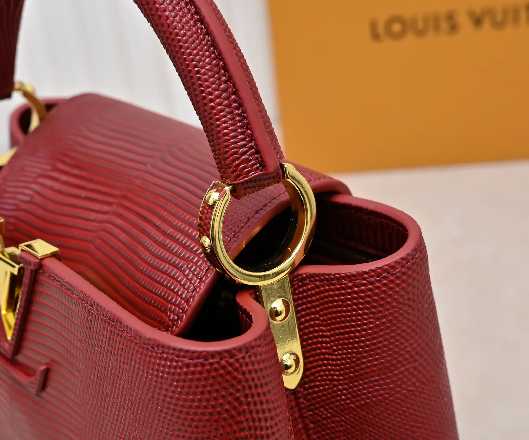 Top-quality original P420 Guangzhou-made M99528 maroon lizard skin gold buckle CapucinesBB handbag exquisitely combines graceful lizard skin outer layer, delicate sheepskin lining and luster metal parts. The iconic flap makes two styles fashionable. The LV logo can be read on the inside and Monogram flowers bloom on the outside. It can light up an eye-catching corner for evening occasions and add a personalized atmosphere to the wardrobe. Shine gorgeous style in day and night occasions.  Detailed features 27 x 18 x 9 cm (length x height x width)