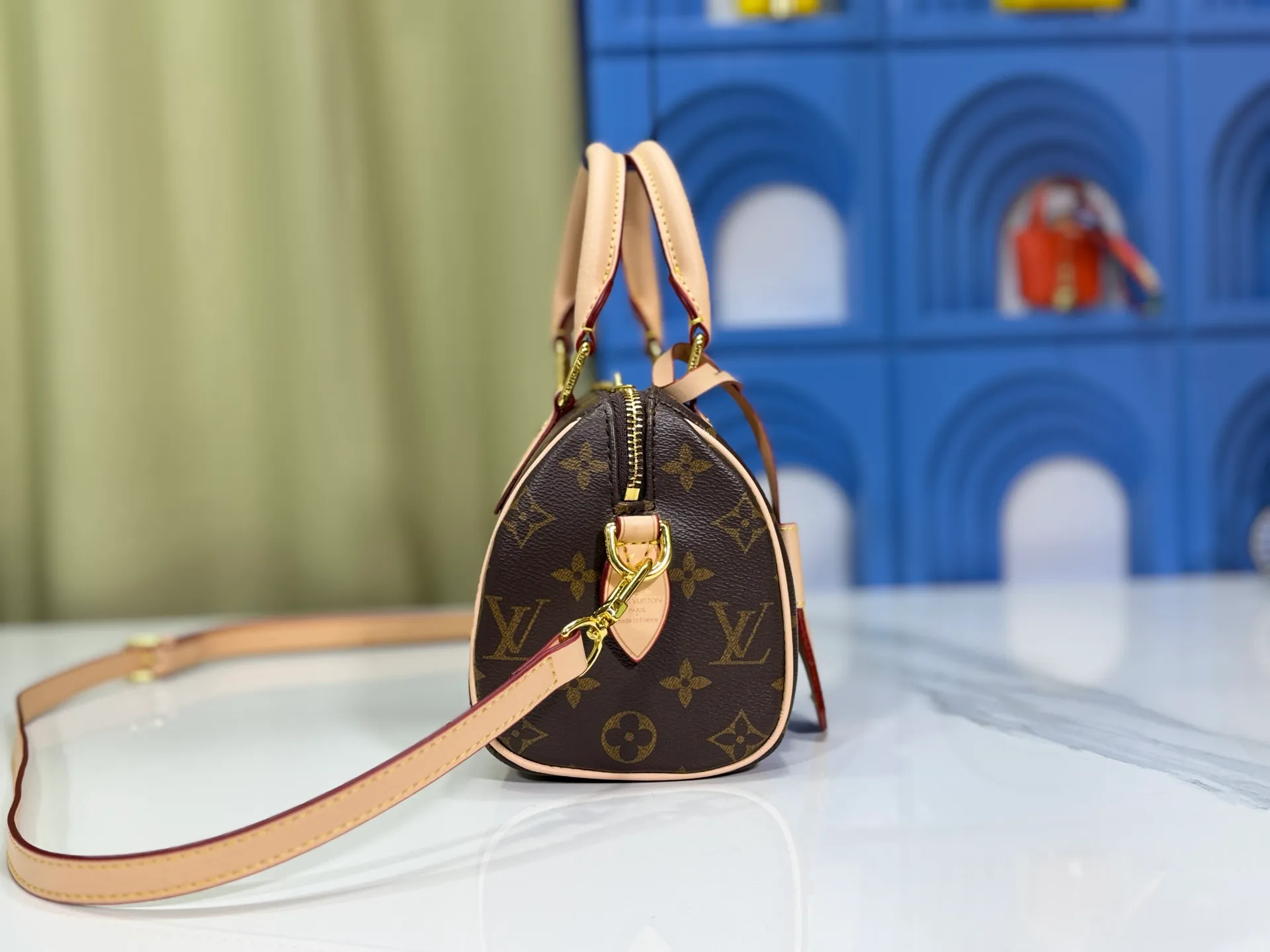 P260 Upgraded from the original version, this M46234 M46222 Speedy Bandoulière 20 handbag is made of soft coated canvas, with the full-length Monogram pattern traced in colorful rainbow tones, highlighting the smart style of the Louis Vuitton x Murakami reissue series. The Toron handle and detachable shoulder strap are constructed of cow leather, the metal corners recall classic luggage elements, and the bow-shaped key bag and padlock add brand touches. Dimensions: 20.5 x 13.5 x 12.0 cm (length x height x width)
