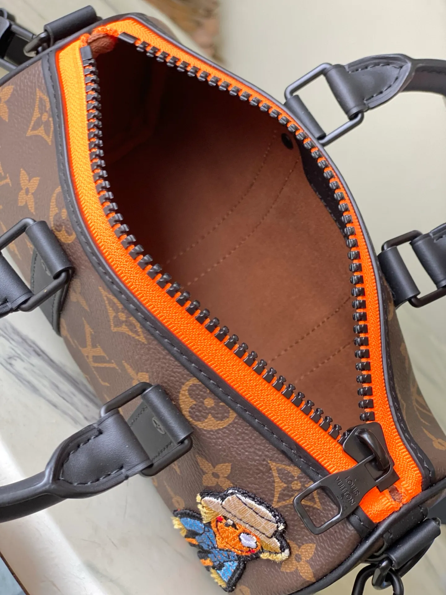 💰840 Top Original M80201 This Keepall Nano men's handbag is a compact version of the brand's original soft travel bag launched in 1930, combining Monogram canvas with black matte leather. A pop of neon orange next to the edge of the zipper makes this classic look pop. The embroidered patches feature cartoon characters from the “Zoom with friends” animated short created by menswear artistic director Virgil Abloh. Dimensions: 12 x 21 x 9 cm